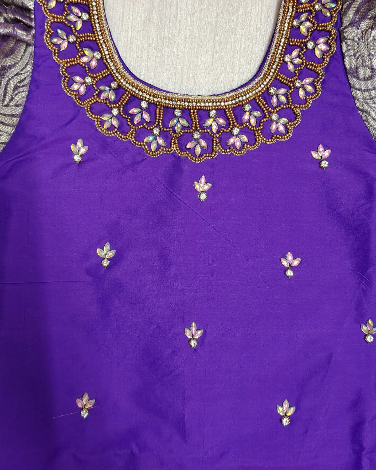 Purple blouse with intricate gold and white beadwork on a plain background