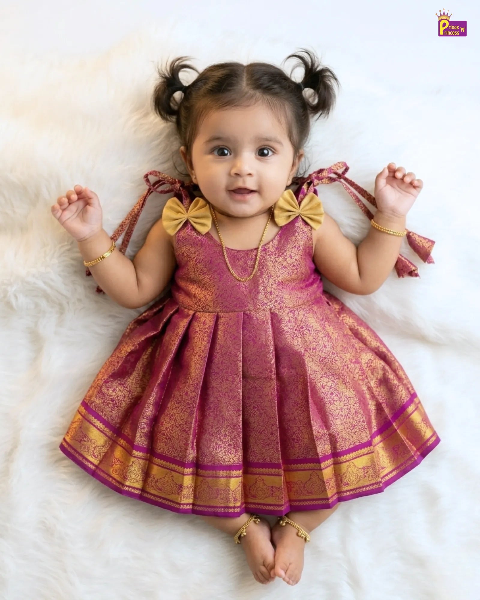 Baby wearing a pink and gold traditional outfit on a white background