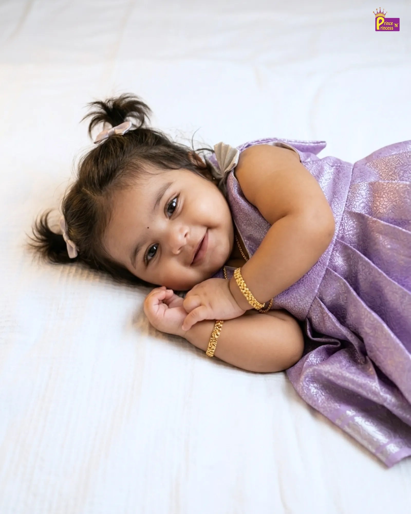 Young girl in a purple dress lying on a white surface