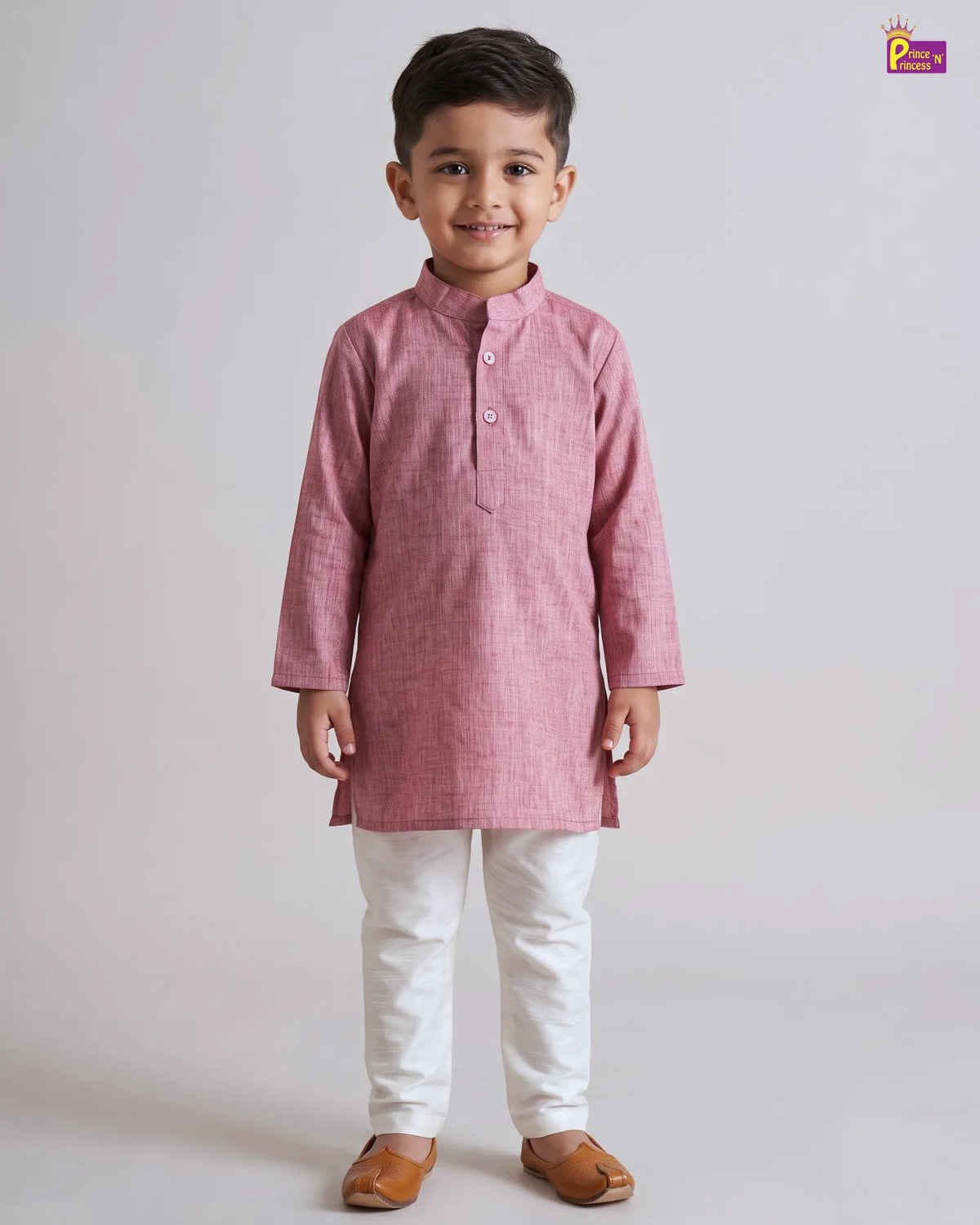 A young boy modeling a pink long-sleeve kurta with white trousers and brown leather sandals, standing against a light gray studio background.