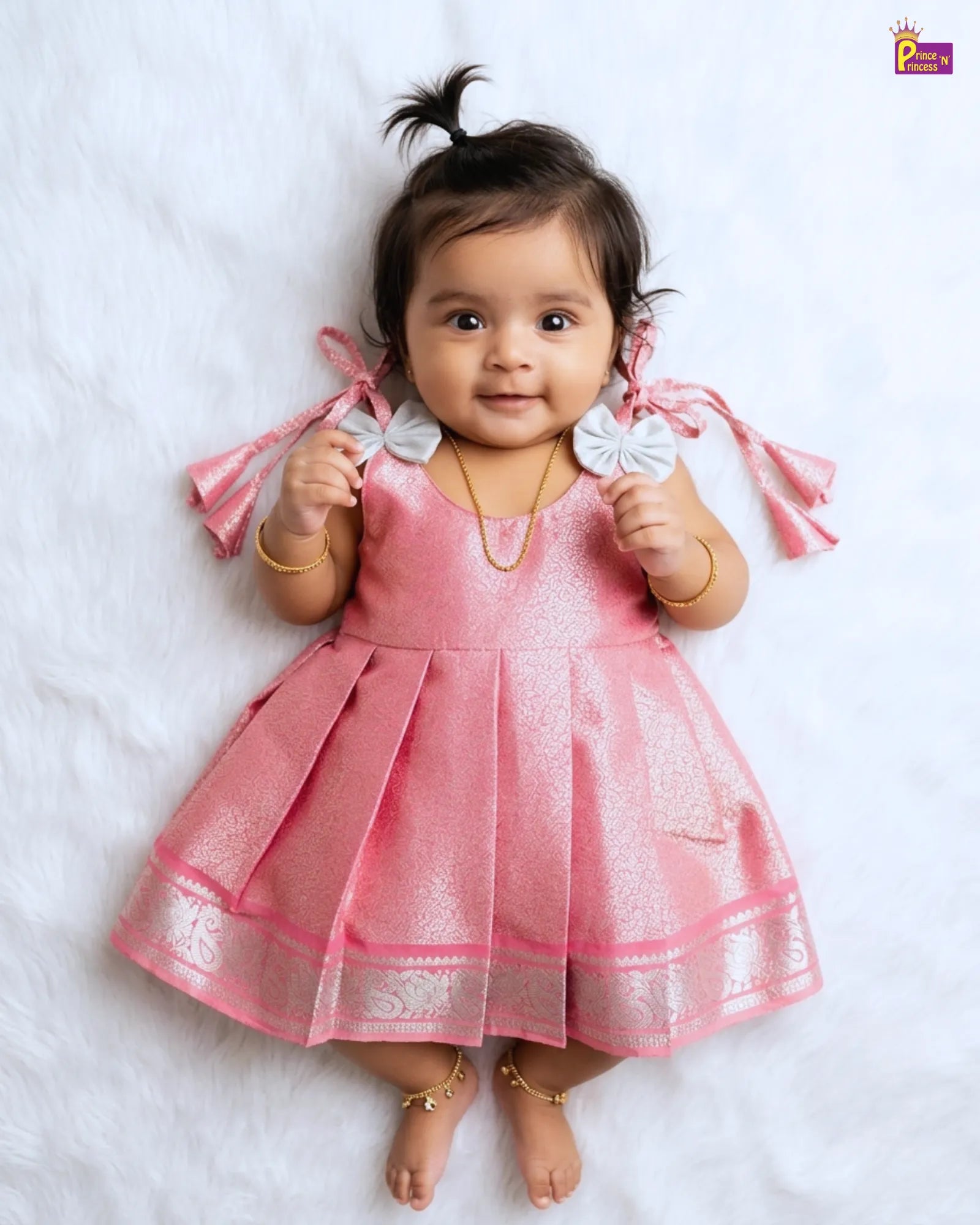 Baby in a pink dress with white accents on a white background