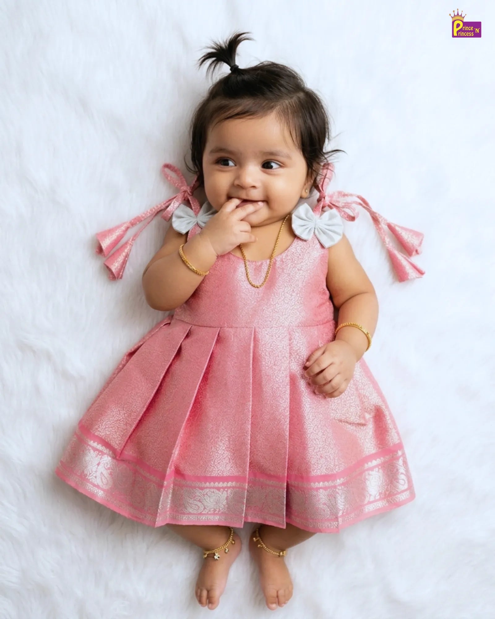 Baby in a pink dress with white accents on a white background