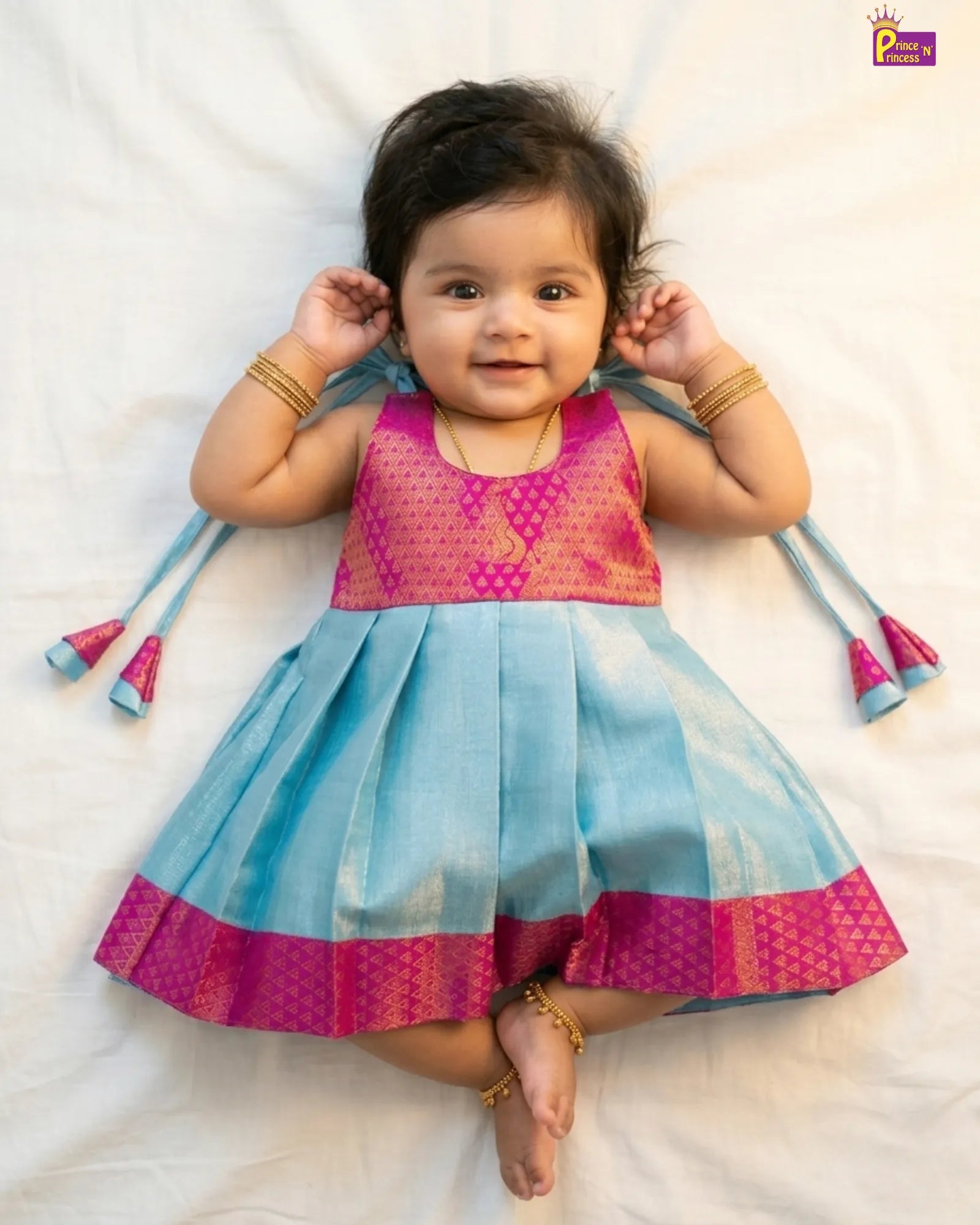 Baby wearing a colorful dress with pink top and blue skirt on a white background