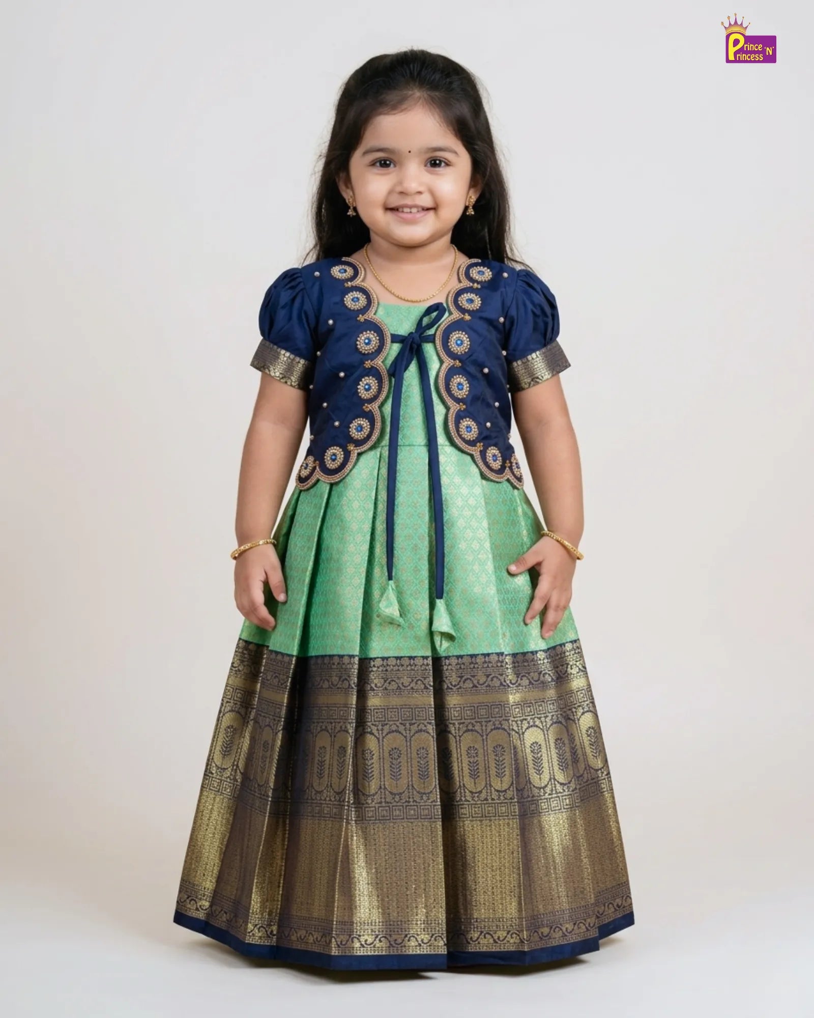 Young girl wearing a green and blue traditional outfit with a white background