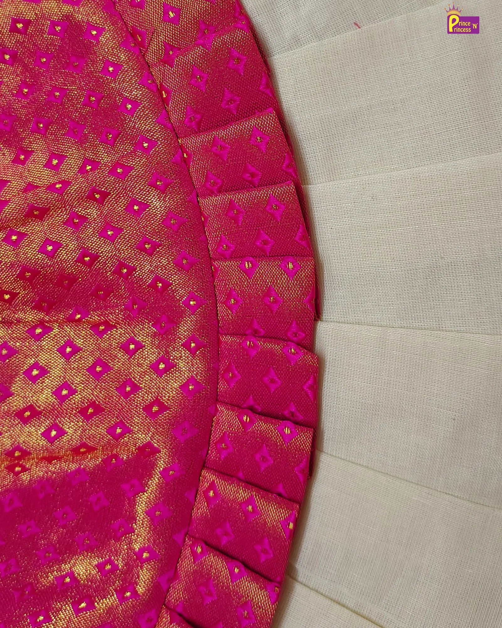 Close-up of a pink and gold patterned fabric with a beige background