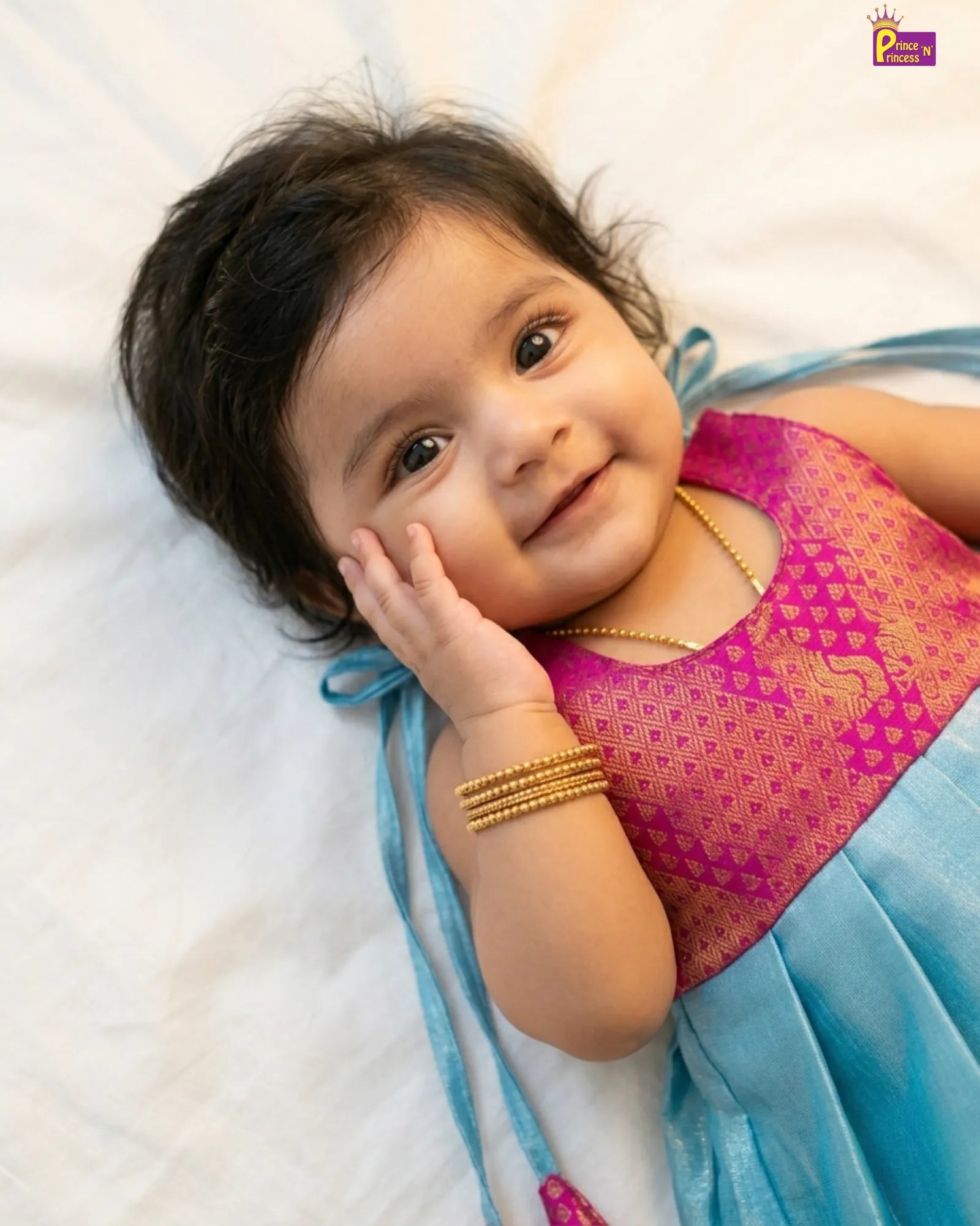 Newborn baby girl in magenta brocade and sky blue silk pattu frock with matching magenta zari border and bow tassel tie by Prince N Princess