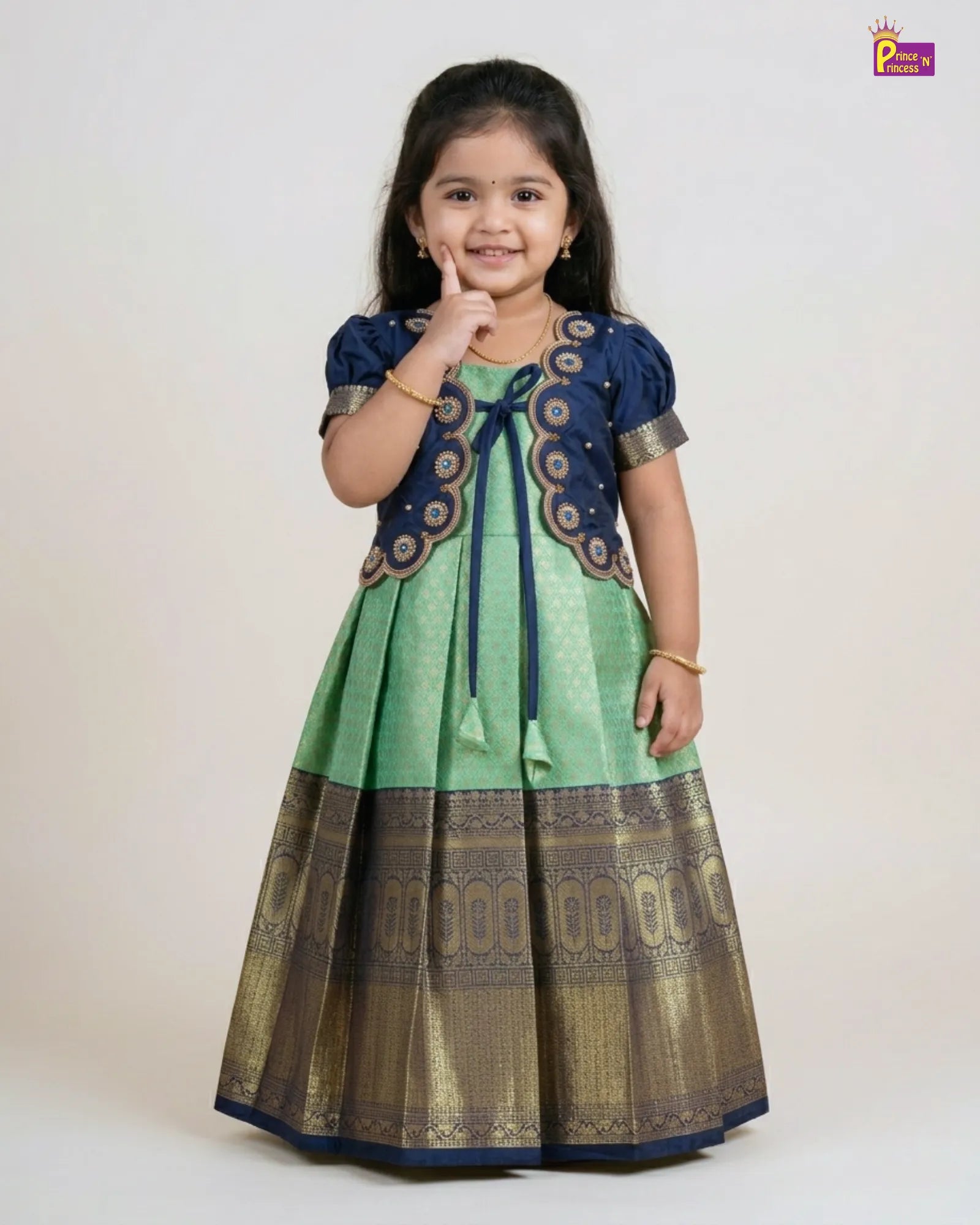 Young girl wearing a green and navy traditional outfit on a white background
