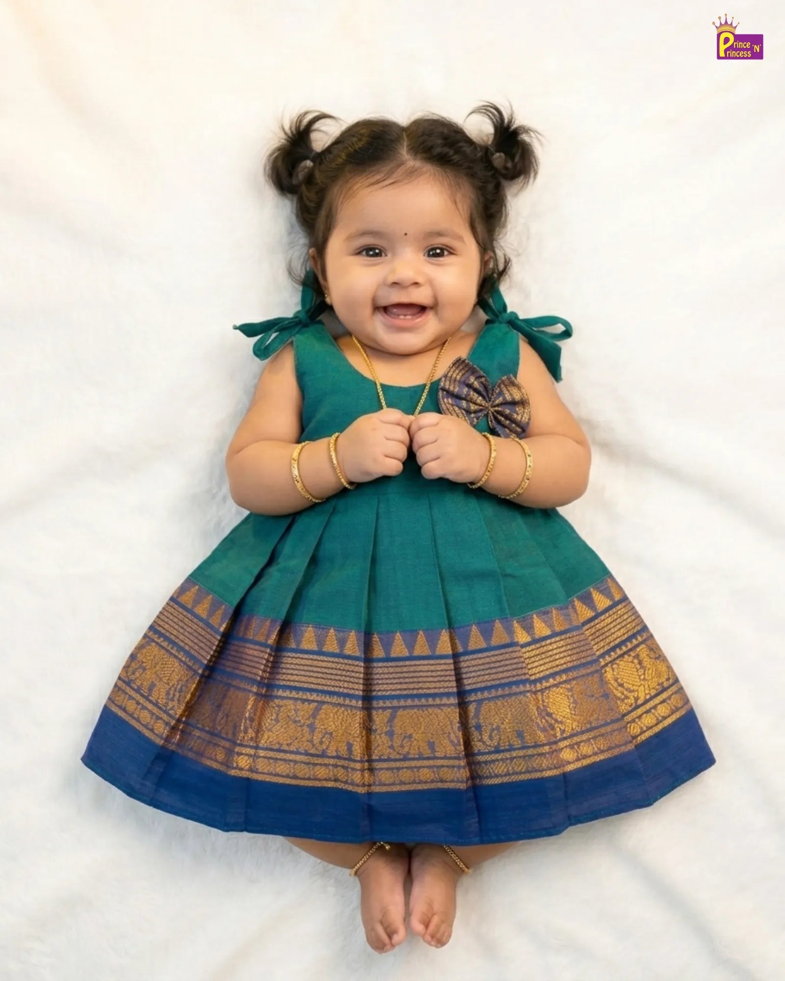 Child wearing a traditional green and blue dress with elephant patterns on a white background