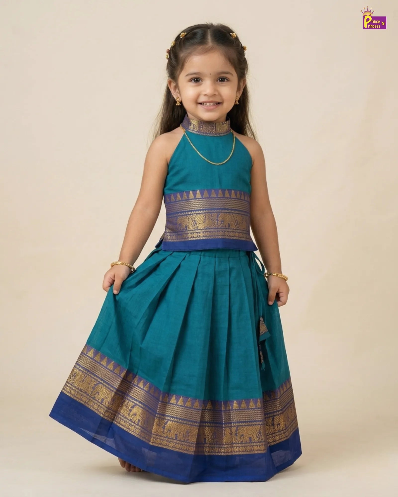 Baby wearing a green and gold traditional outfit with tassels on a white background