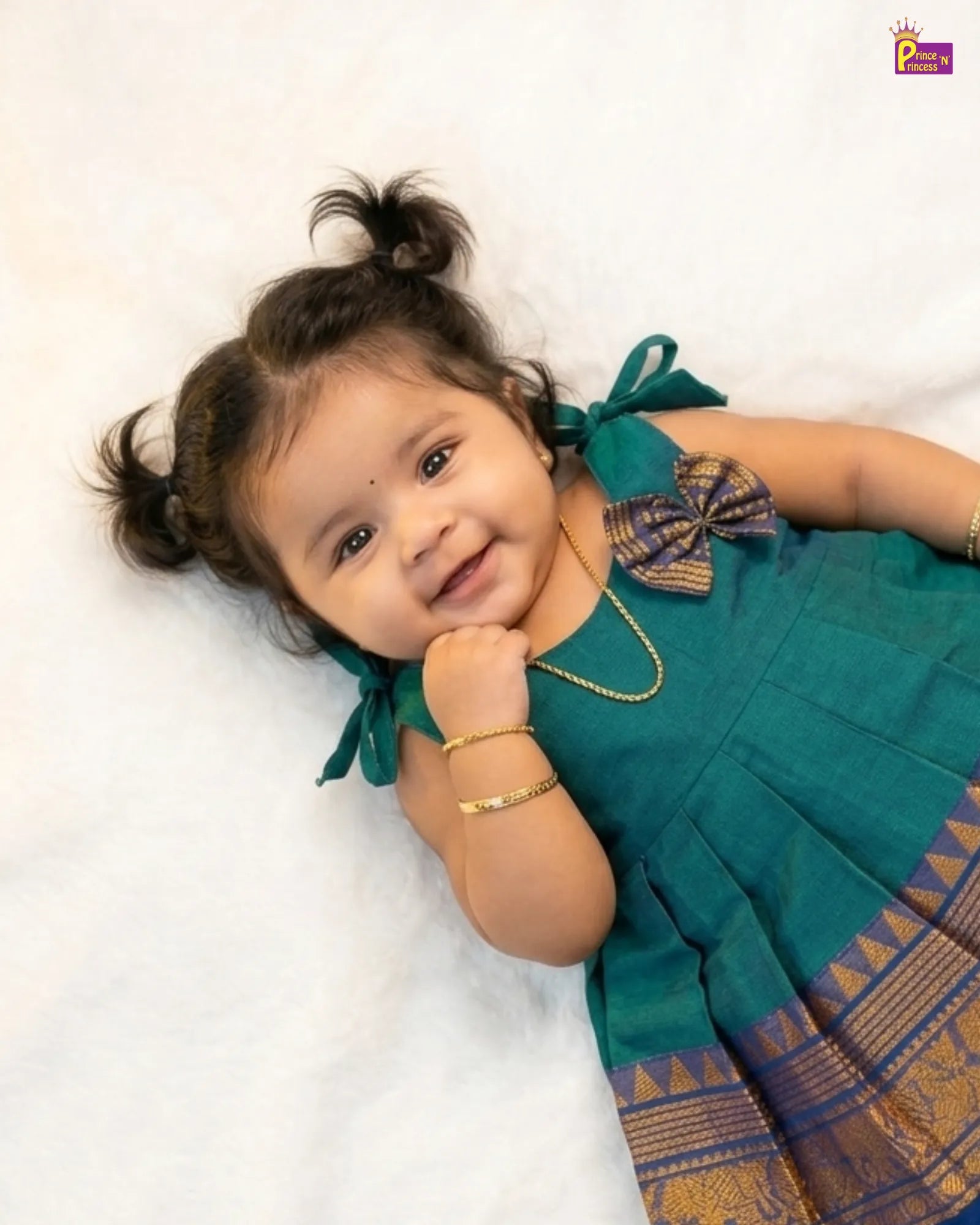 Child wearing a green traditional outfit with a decorative bow on a white background