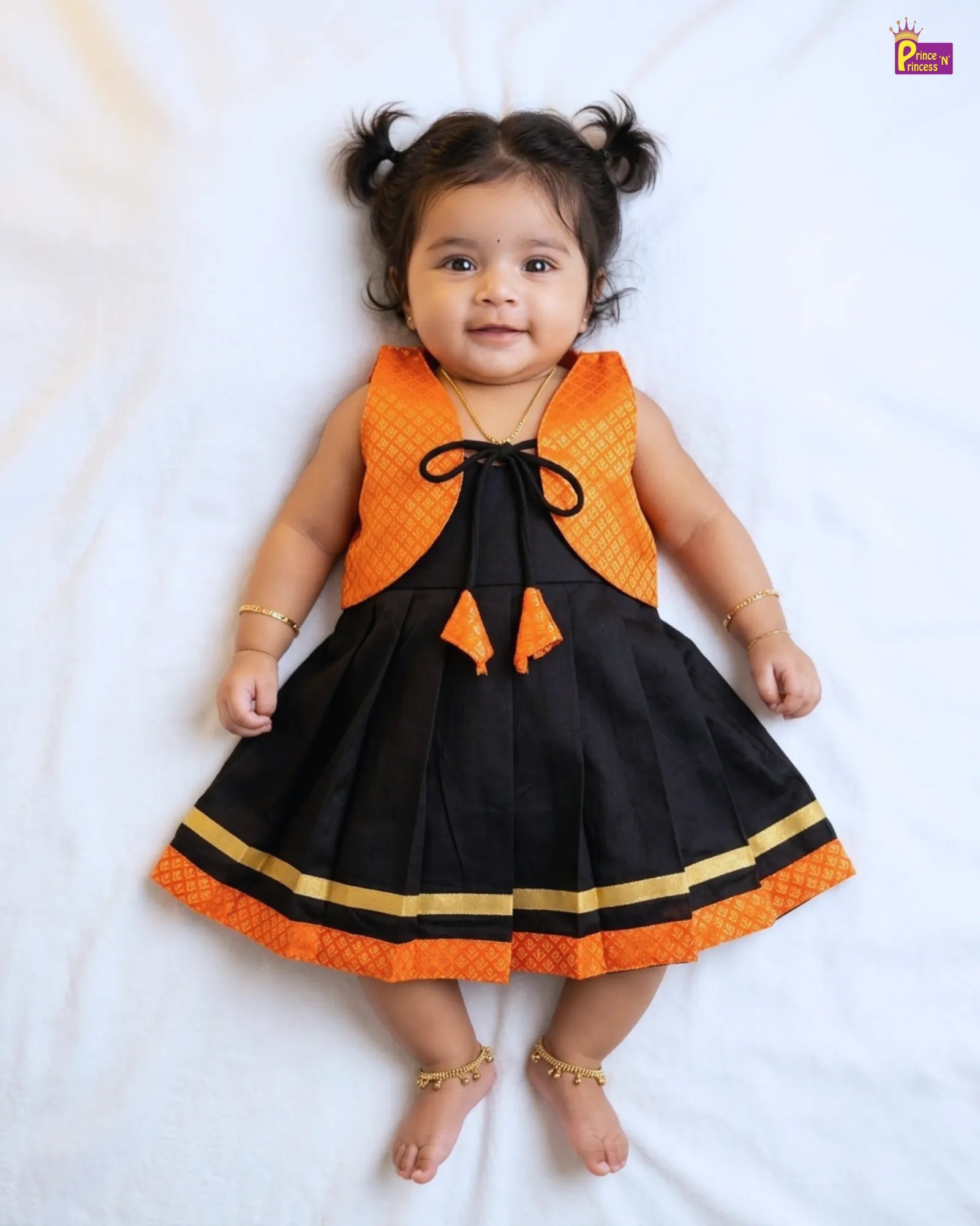 Baby wearing a black and orange dress on a white background