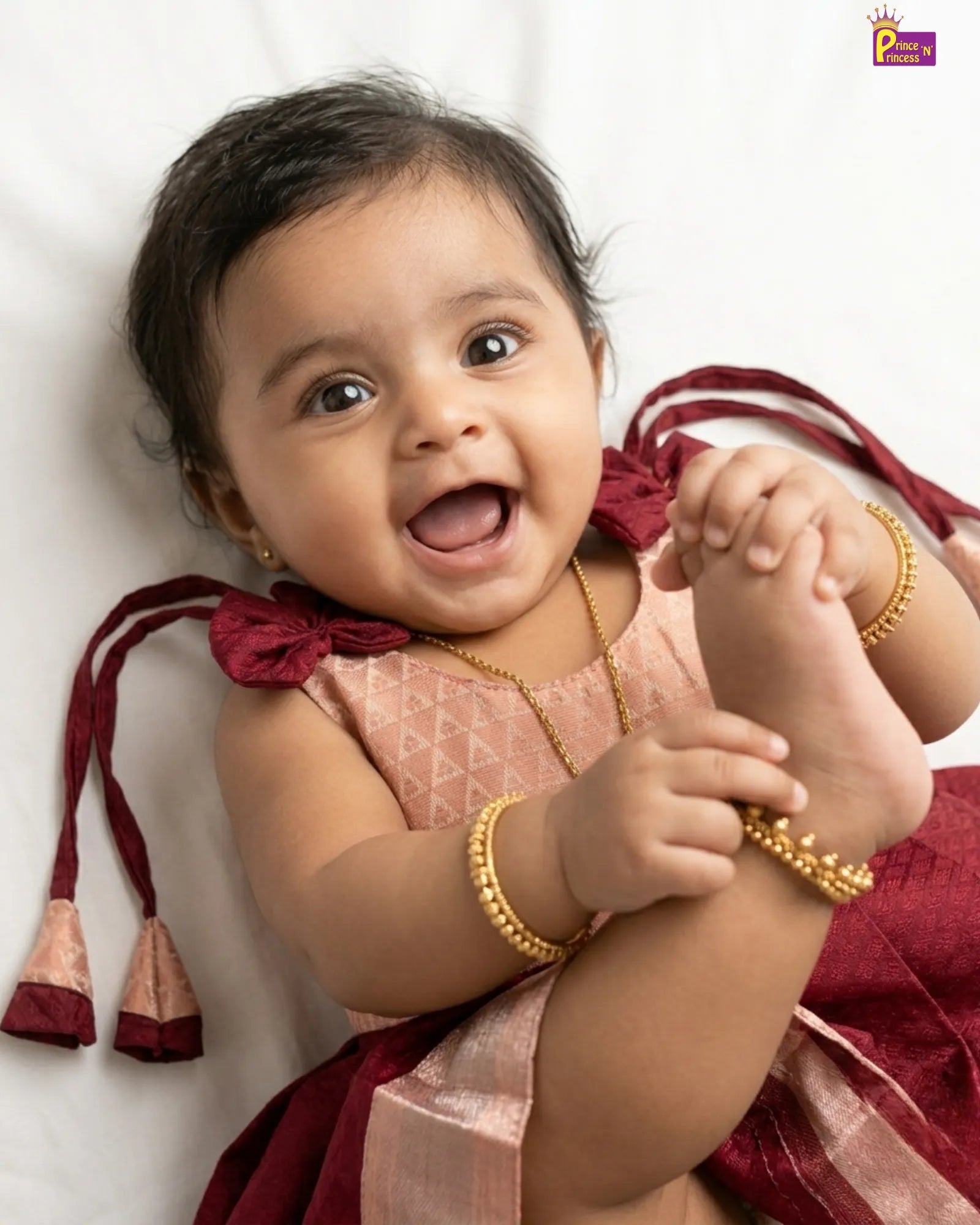 Baby wearing a light-colored dress with pink accents on a white background