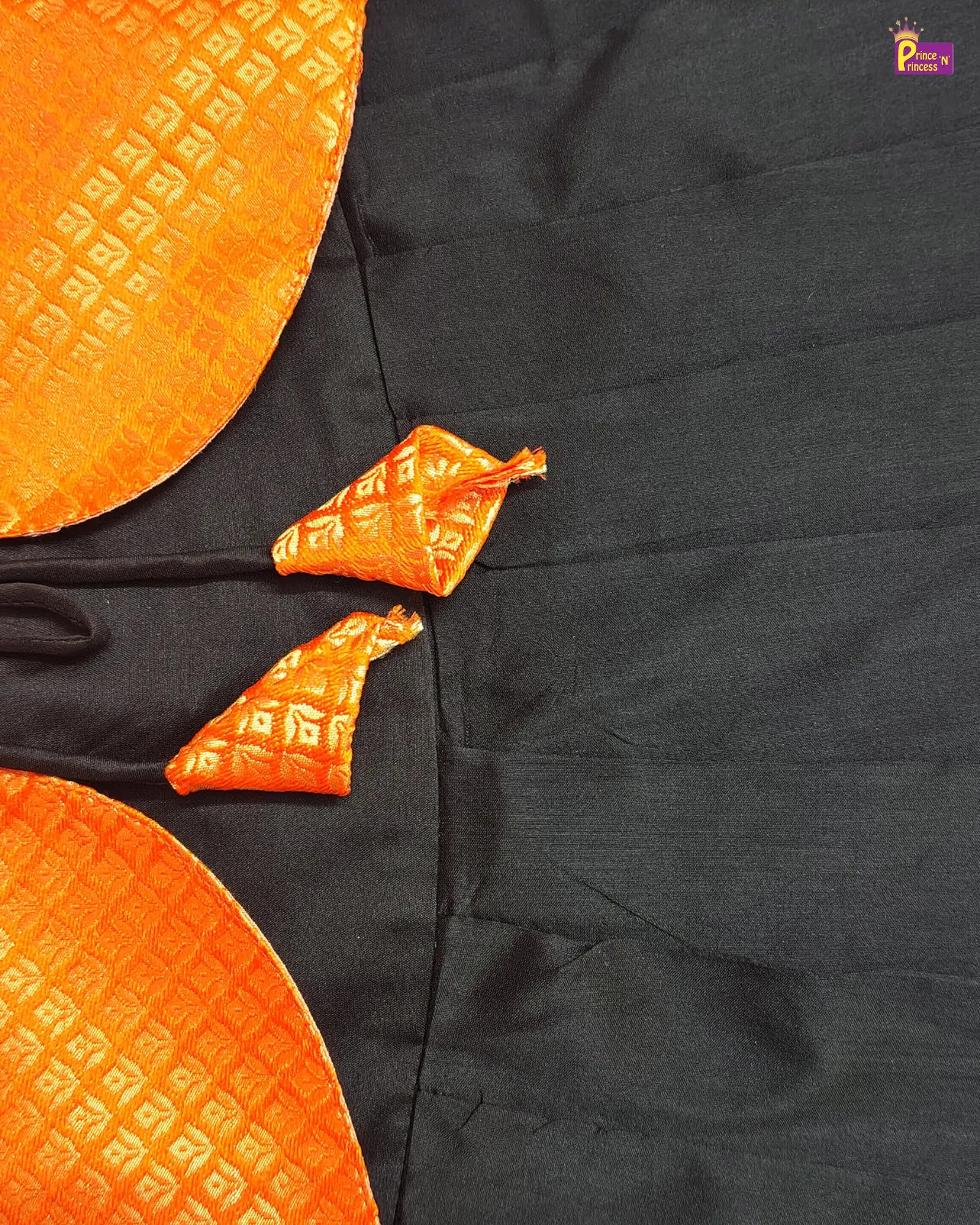 Black fabric with orange decorative patterns on a plain background