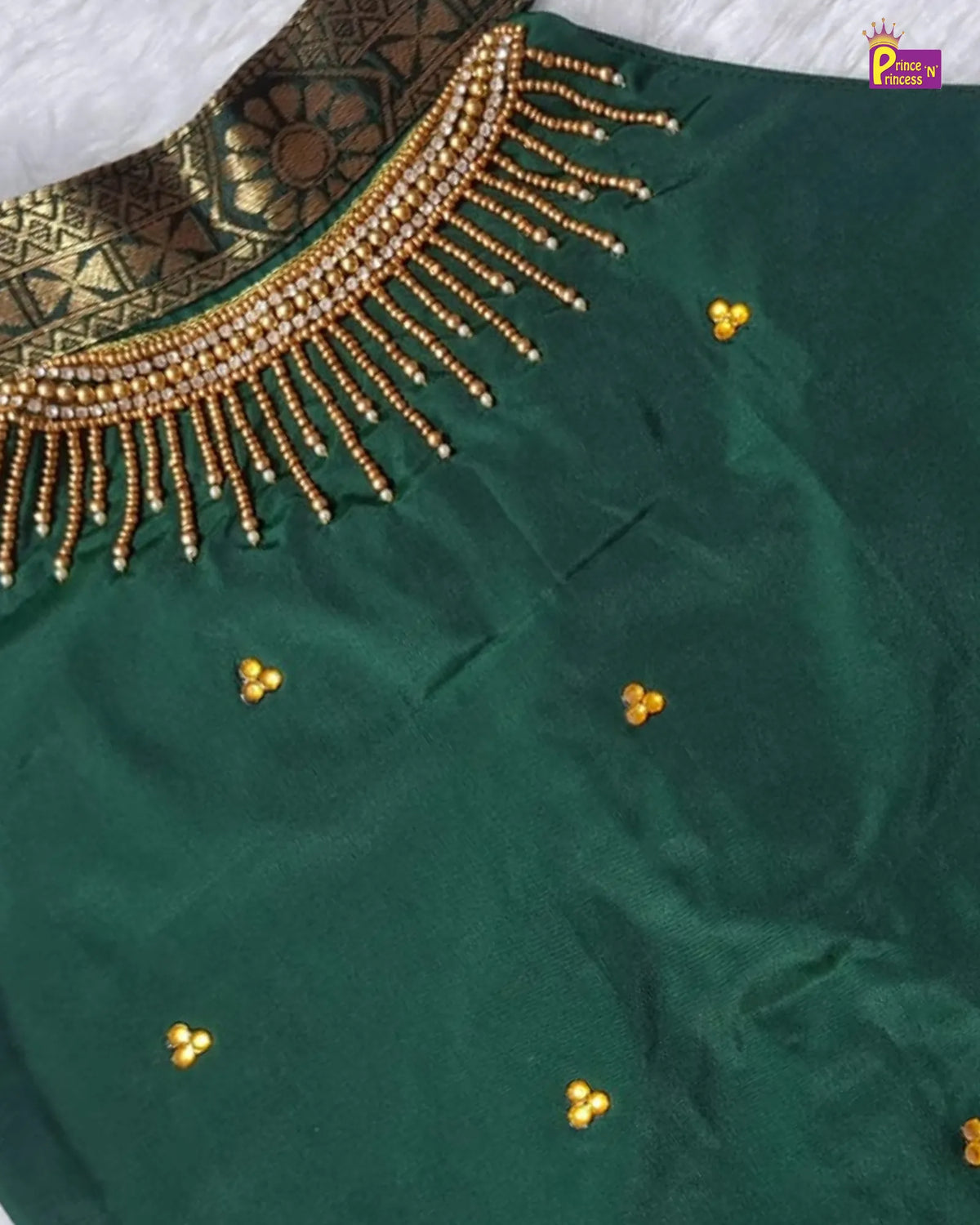 A close-up of a dark green fabric garment, likely a saree or dress, featuring a wide gold beaded neckline border and small gold floral motifs scattered across the fabric.