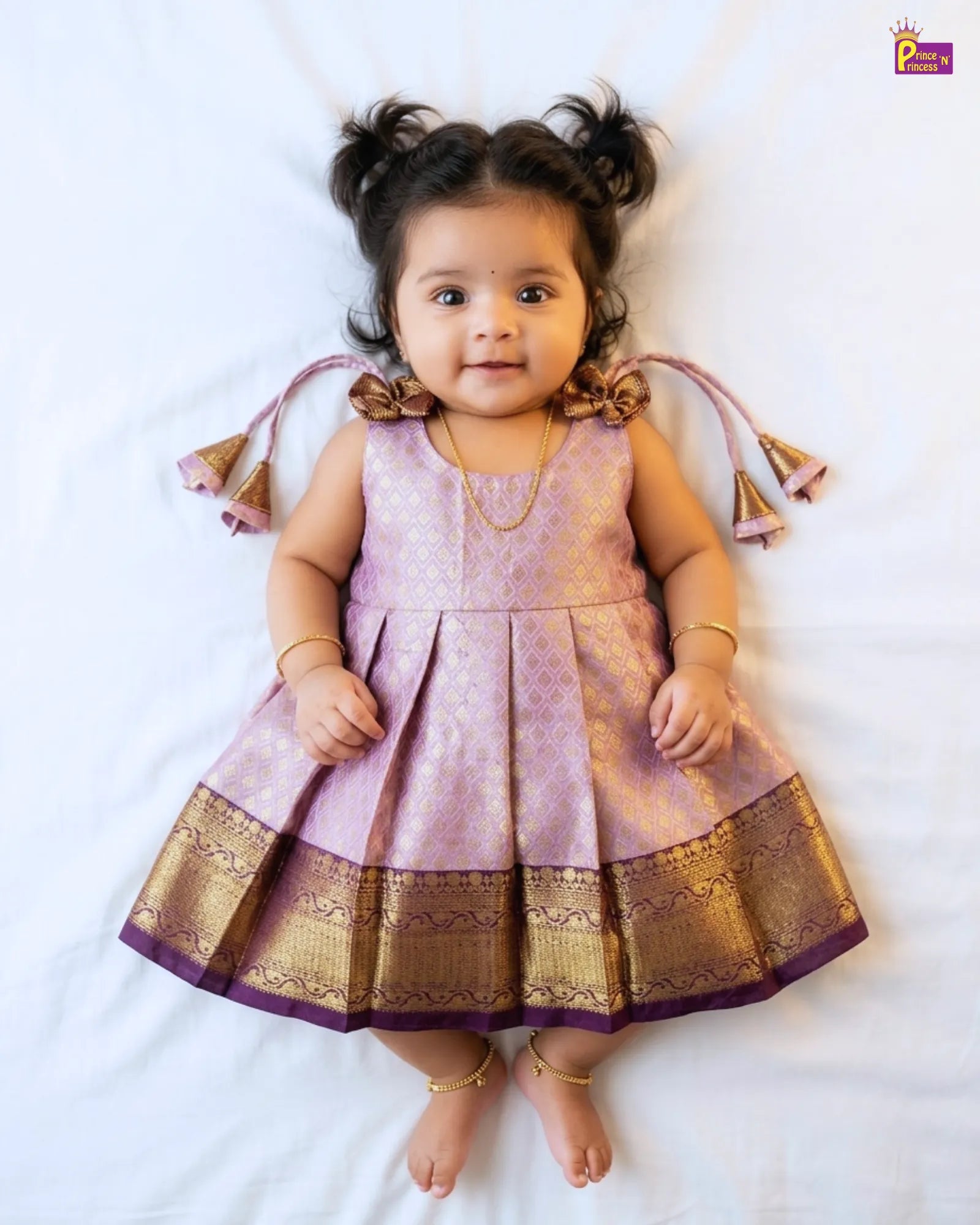 Baby wearing a pink and gold traditional outfit on a white background