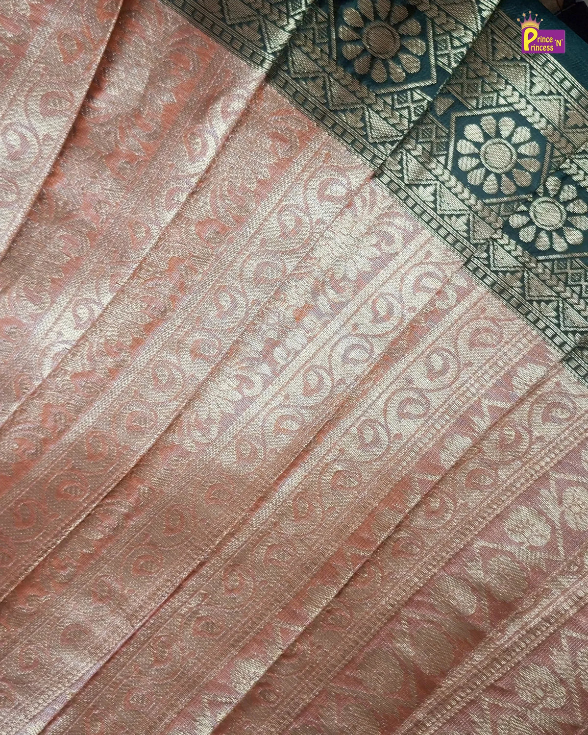 A close-up of a peach-pink and gold Banarasi silk saree body with intricate zari woven patterns, featuring a dark teal border with gold floral motifs.