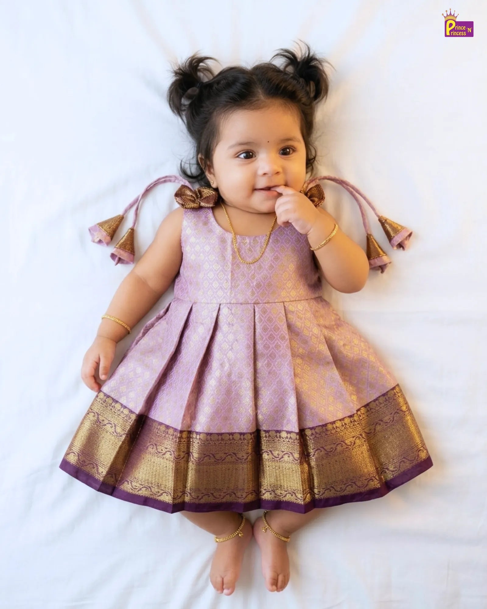 Child wearing a pink and gold traditional outfit on a white background