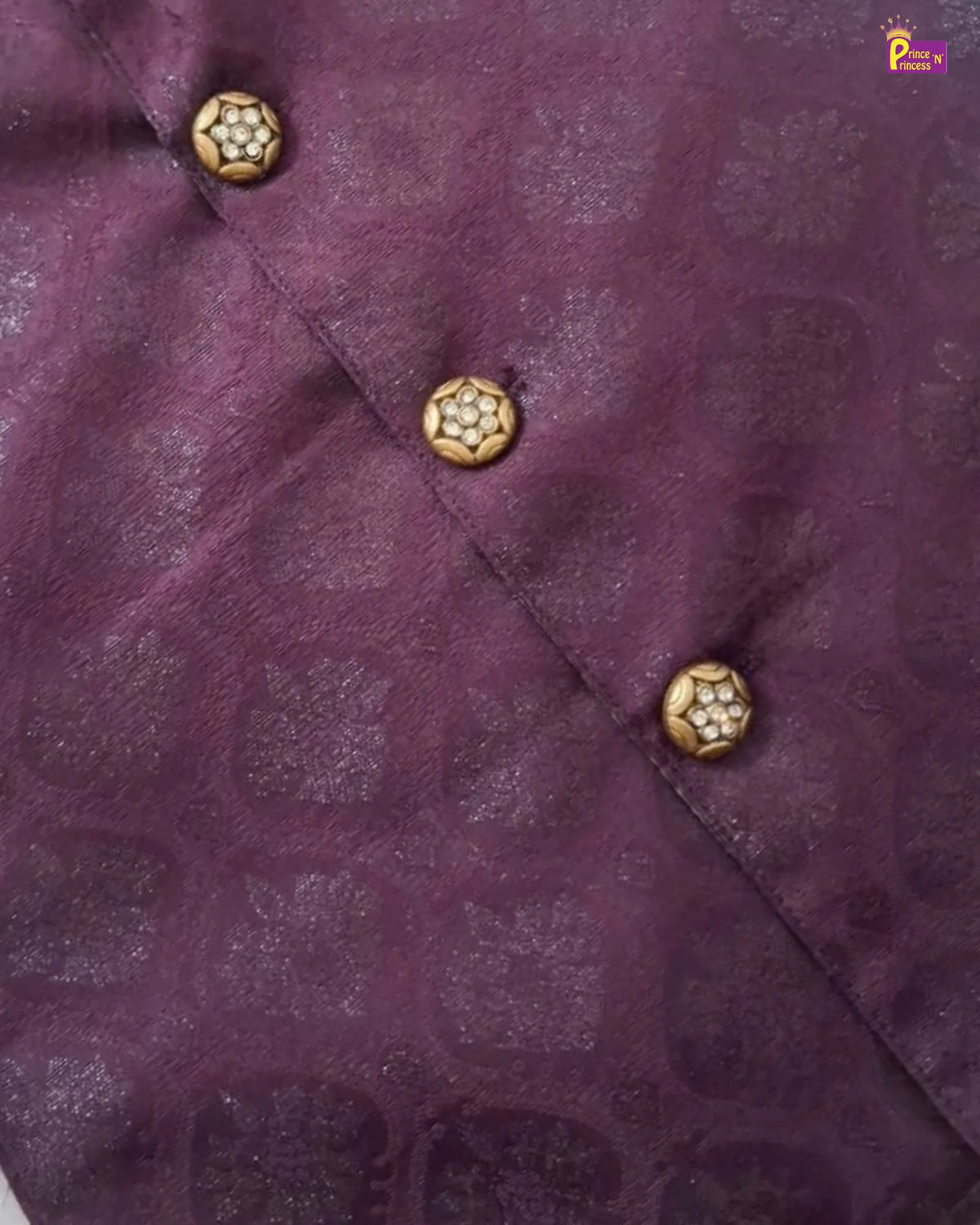 Close-up of a purple fabric garment with a subtle tonal jacquard pattern and decorative gold-toned buttons arranged diagonally.