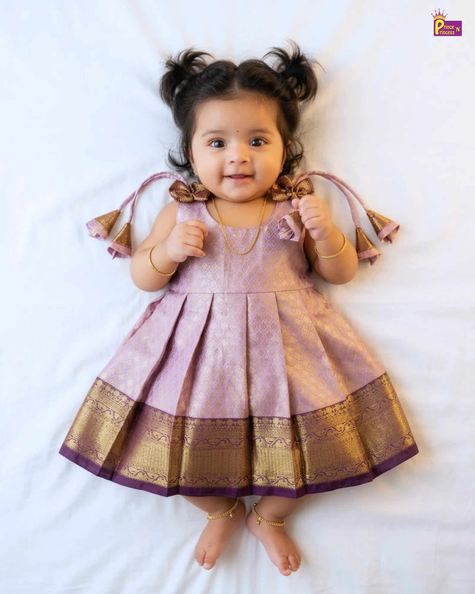 Child wearing a pink traditional outfit with gold accents on a white background