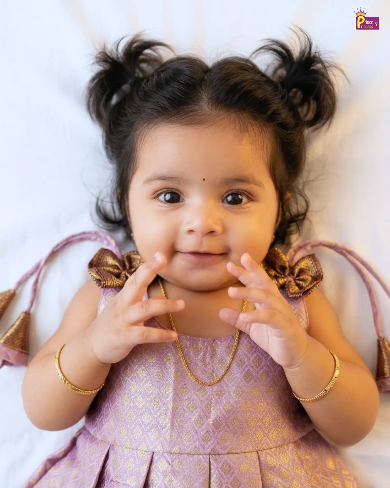 Baby girl in a pink dress with gold accents on a white background