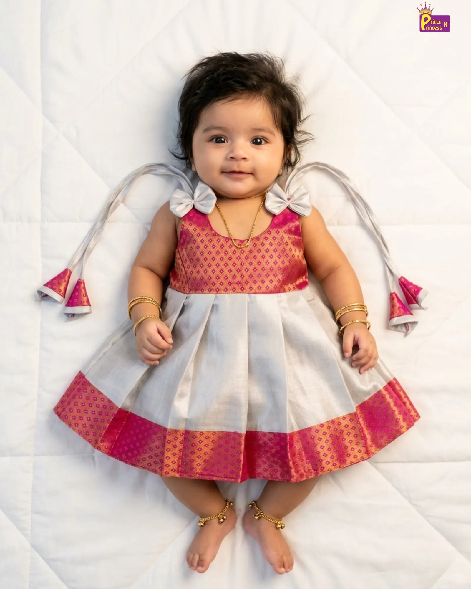Baby wearing a traditional outfit with pink and white colors on a white background