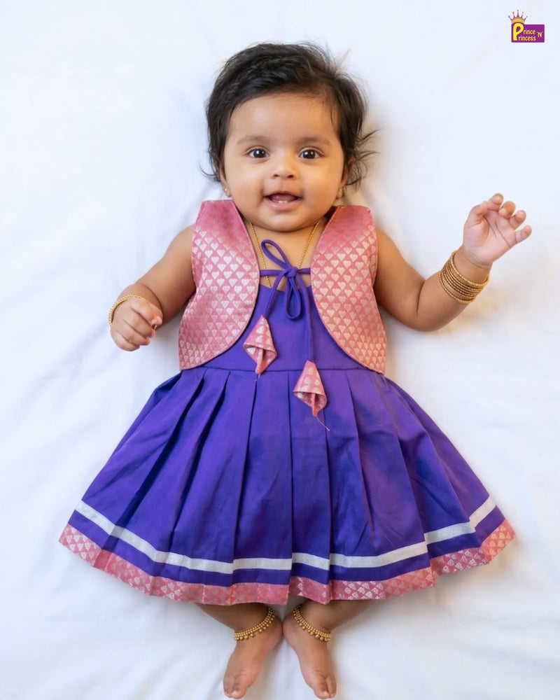 Baby wearing a purple dress with a pink vest on a white background