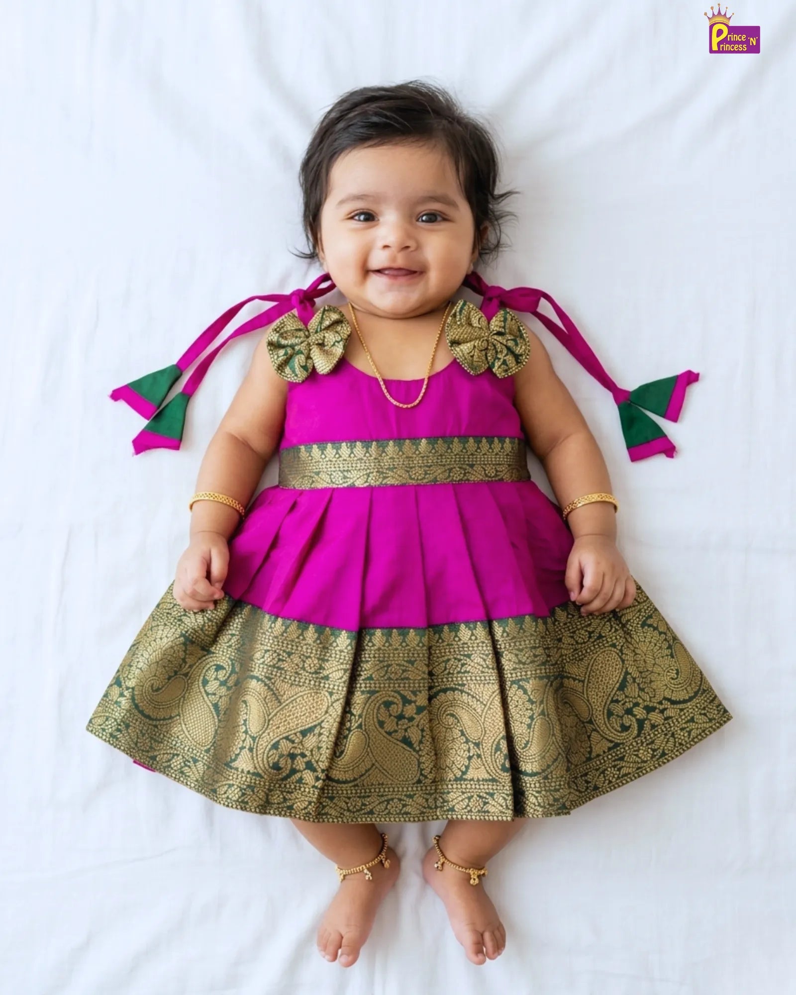 Baby wearing a pink and gold traditional outfit on a white background