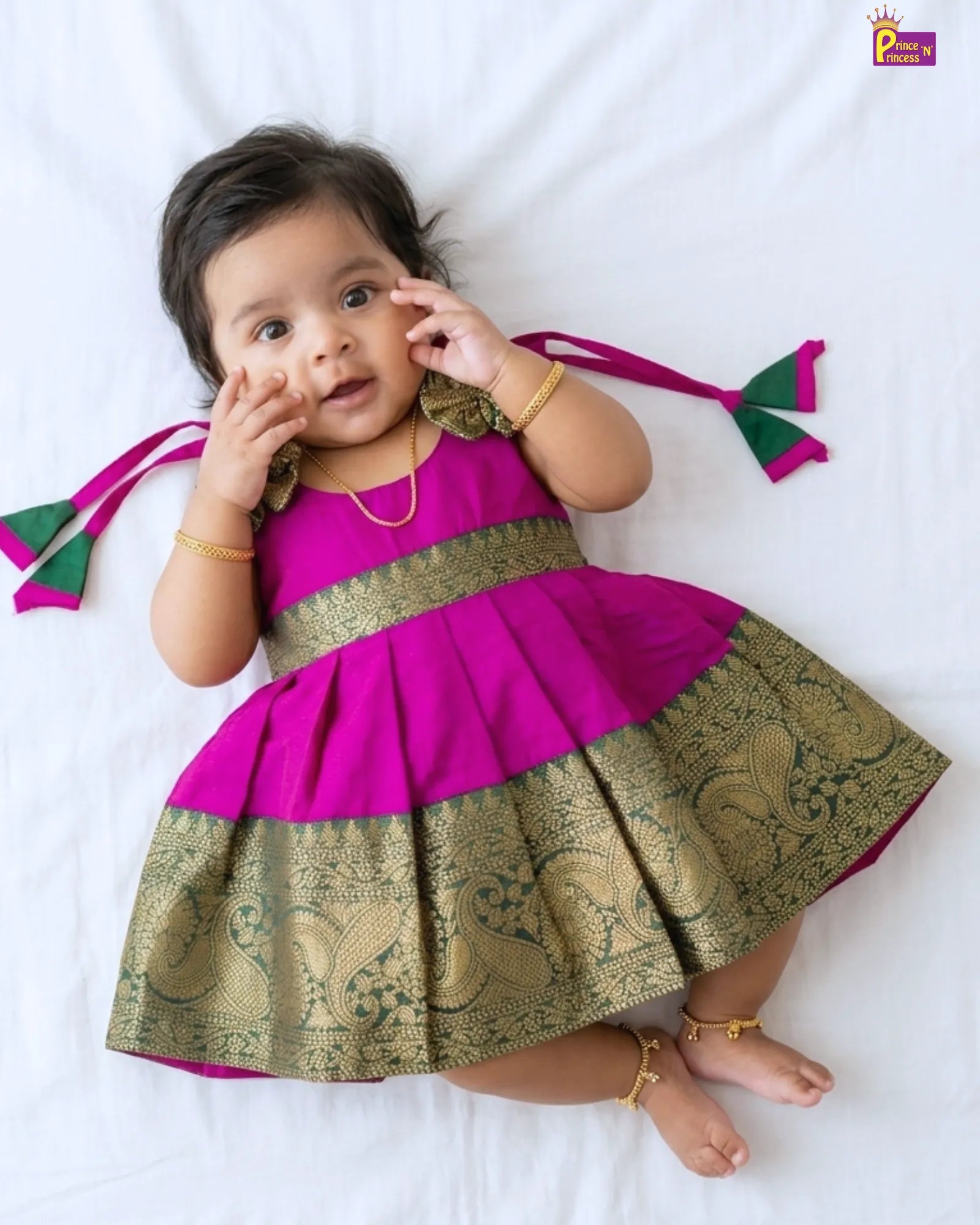 Baby wearing a pink and gold dress on a white background