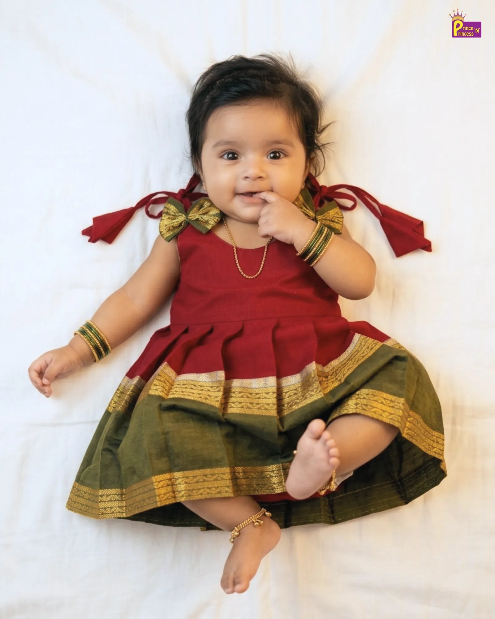 Baby wearing a traditional outfit with red and green colors on a white background