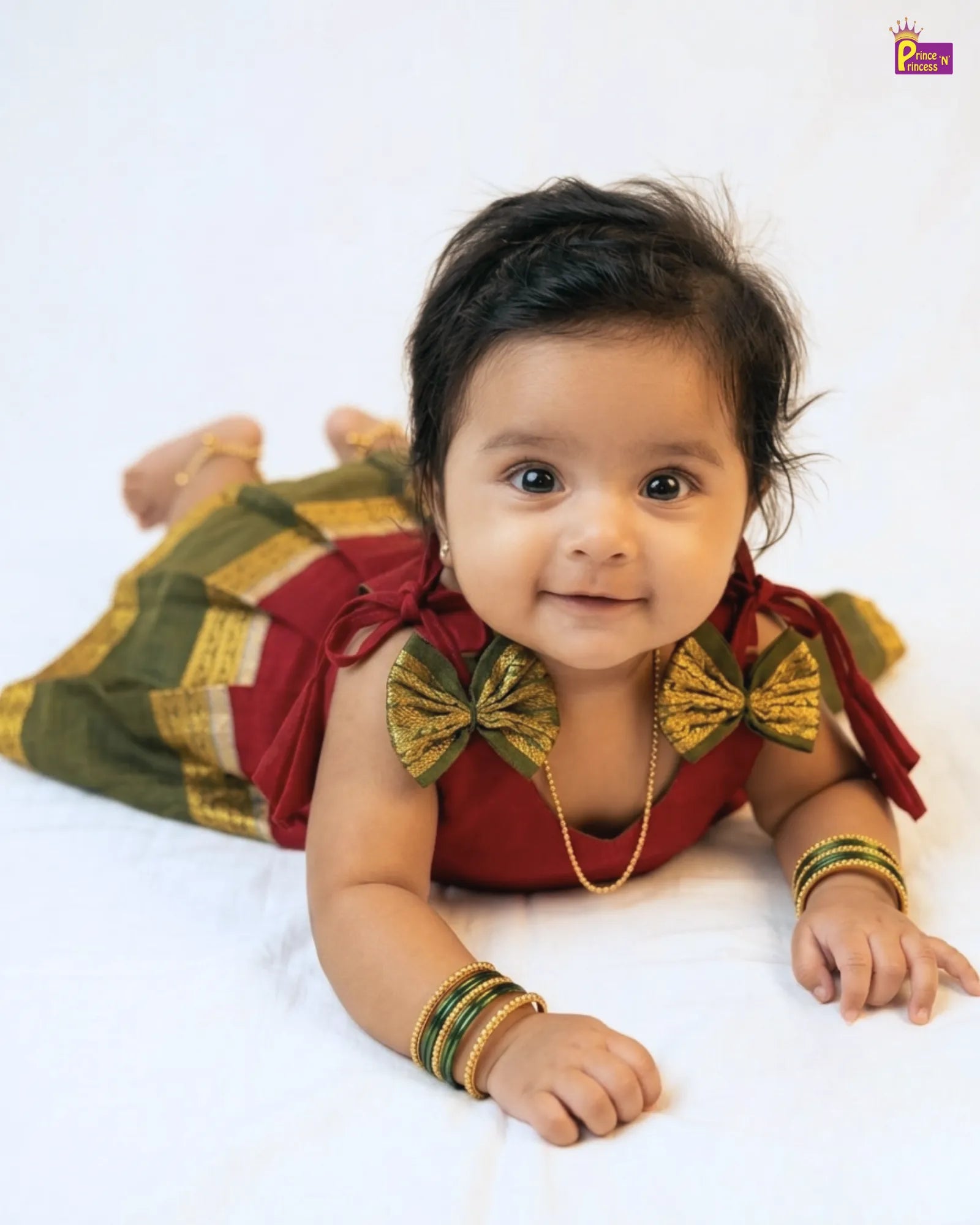 Baby wearing traditional attire with decorative elements on a white background