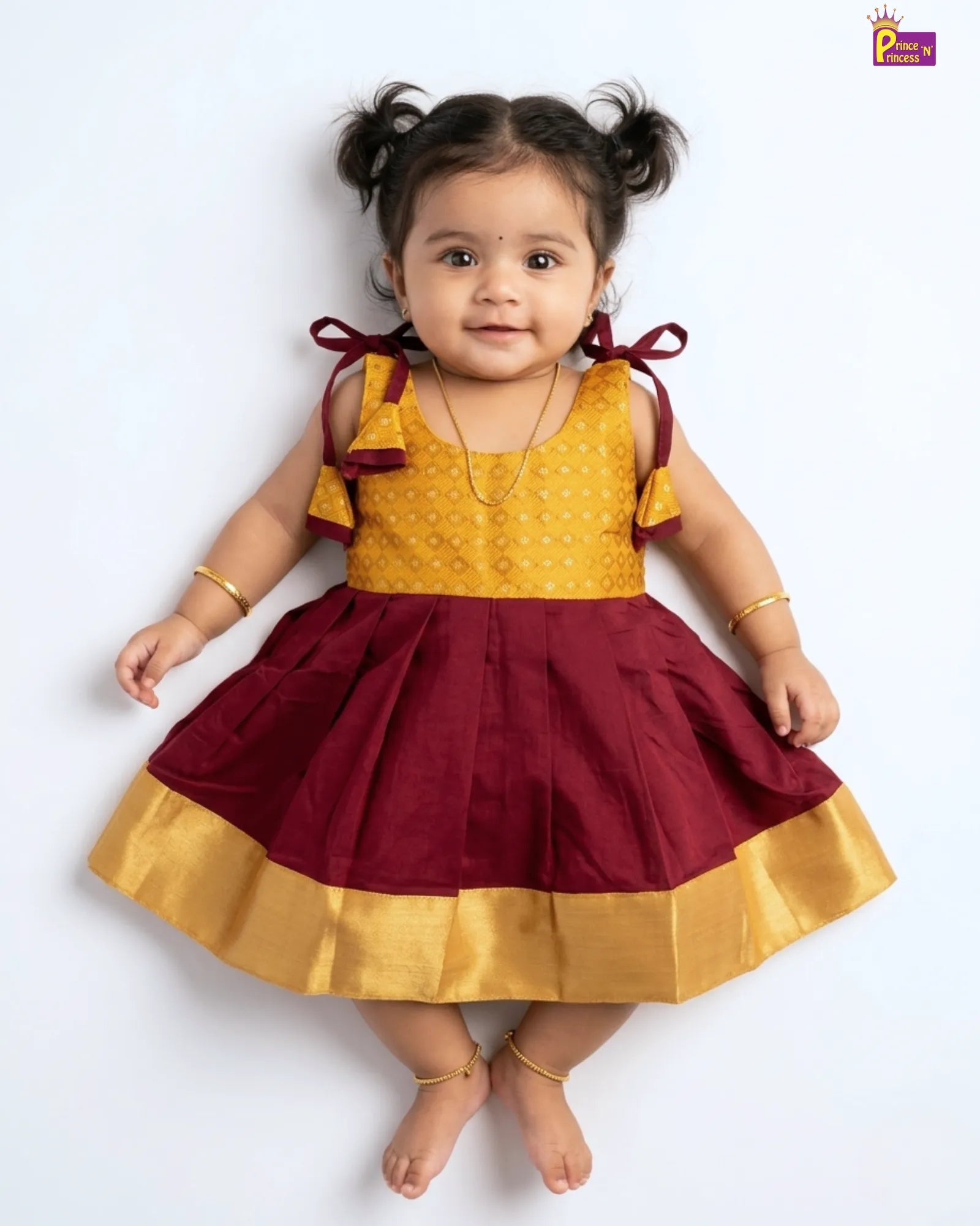 Child wearing a yellow and maroon dress with ruffled sleeves on a white background