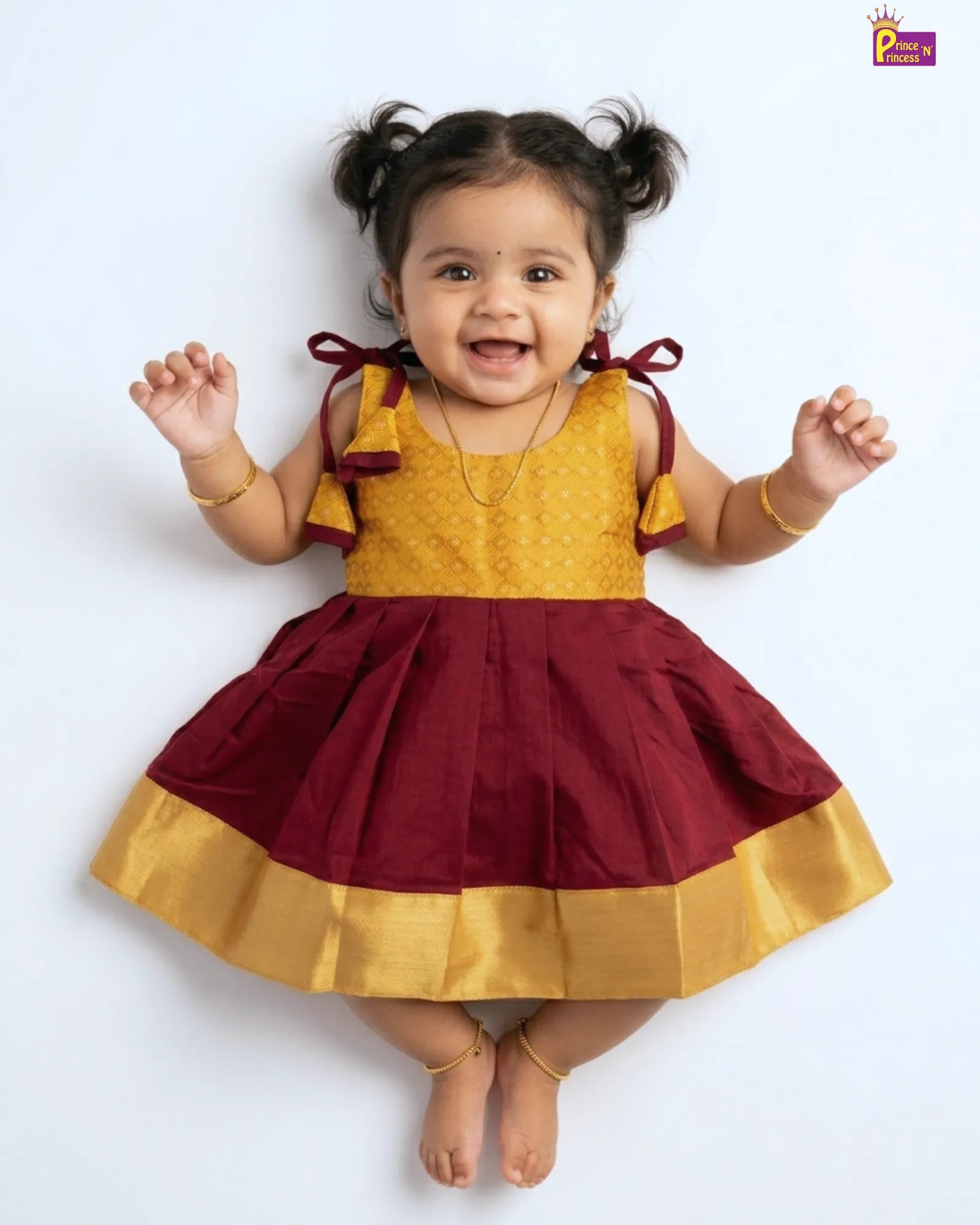 Child wearing a yellow and maroon dress with a white background
