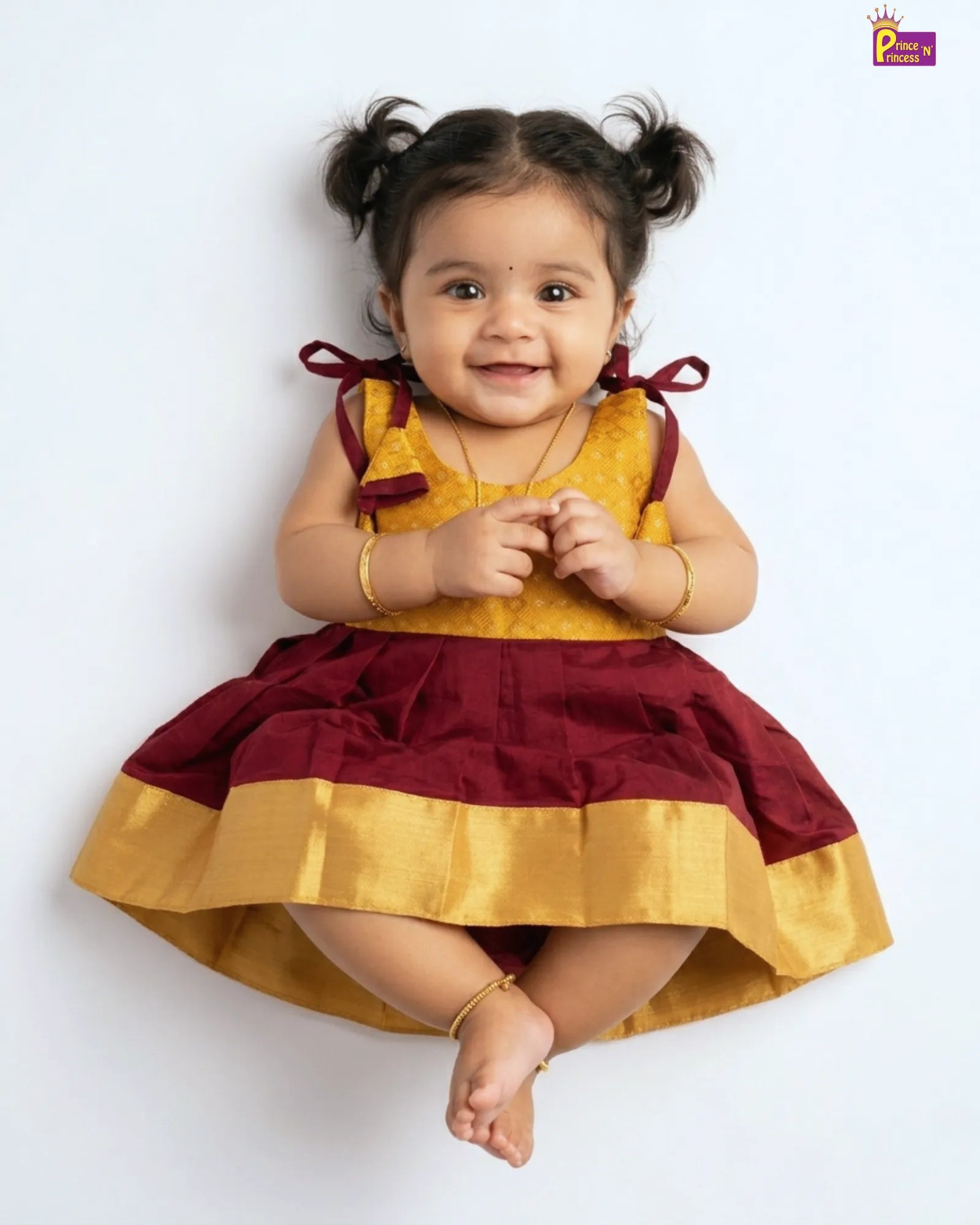 Child wearing a yellow and maroon dress on a white background