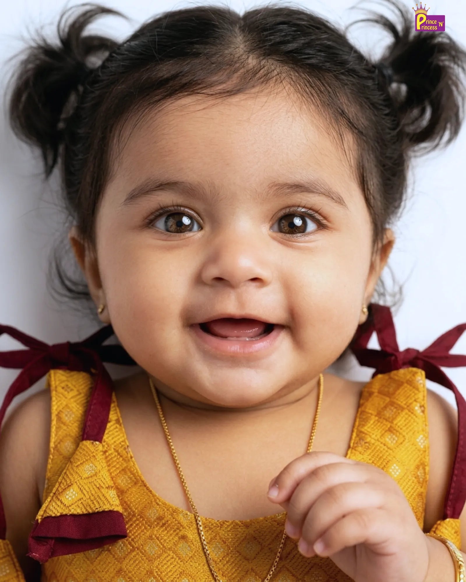 Child with pigtails wearing a yellow outfit against a white background