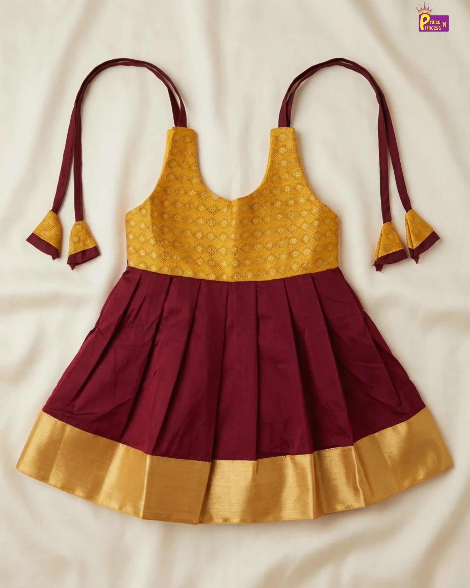 Maroon and yellow traditional dress with tassels on a beige background