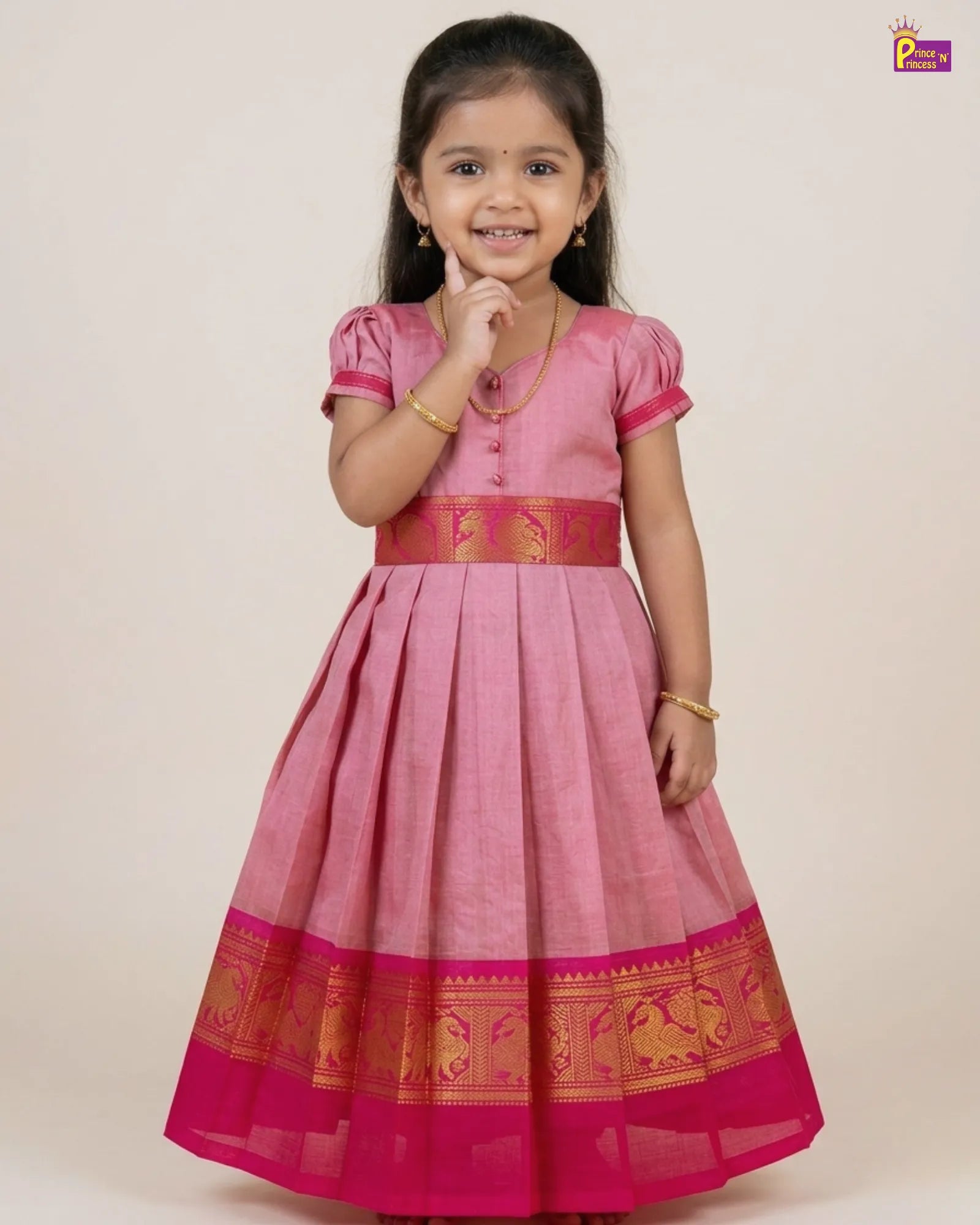 Baby wearing a traditional outfit with a gold and maroon dress on a white background