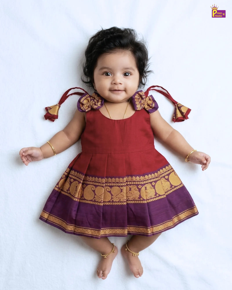 Child wearing a red and purple traditional outfit with gold patterns on a white background