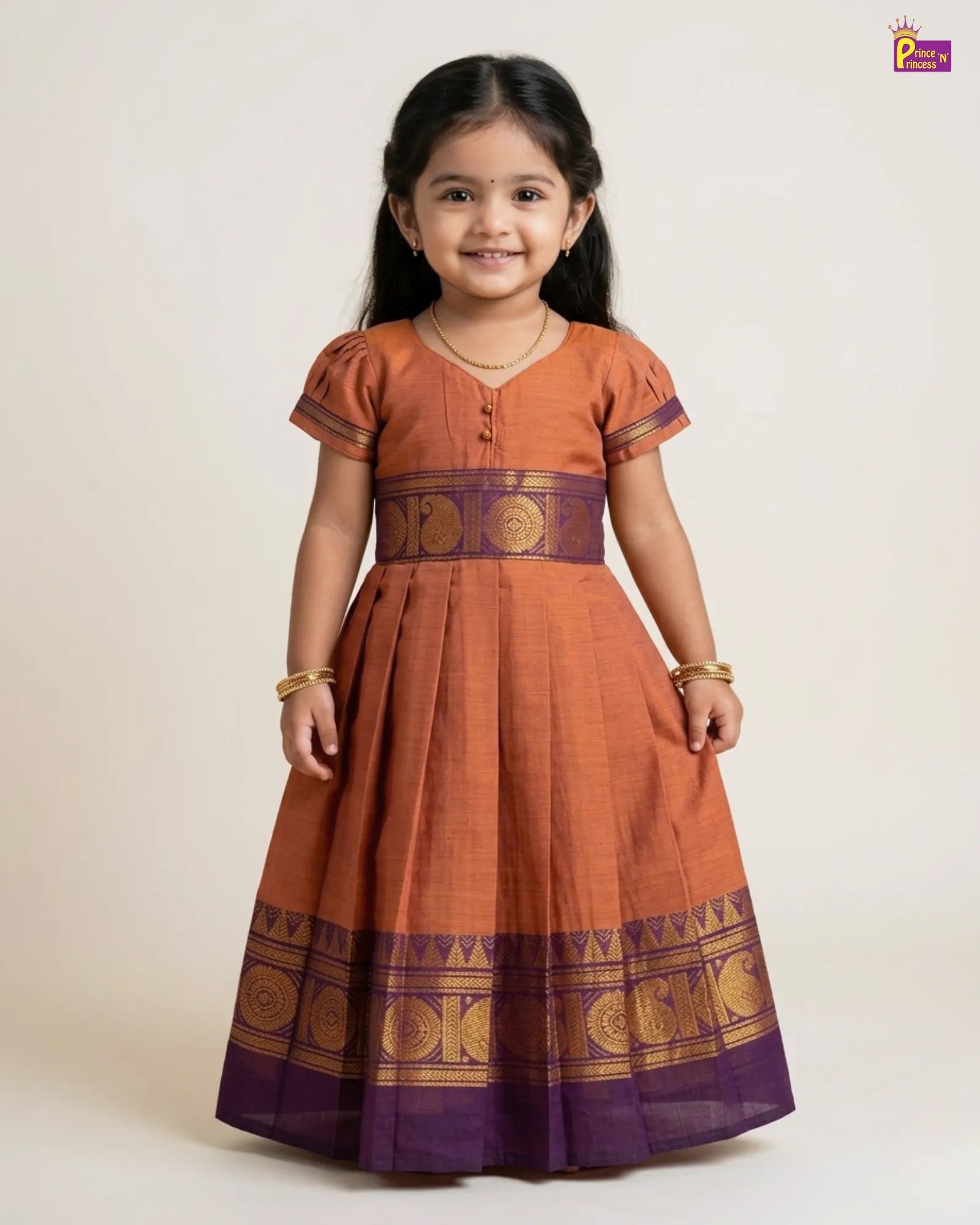 Young girl wearing a traditional orange and purple dress with gold patterns on a white background