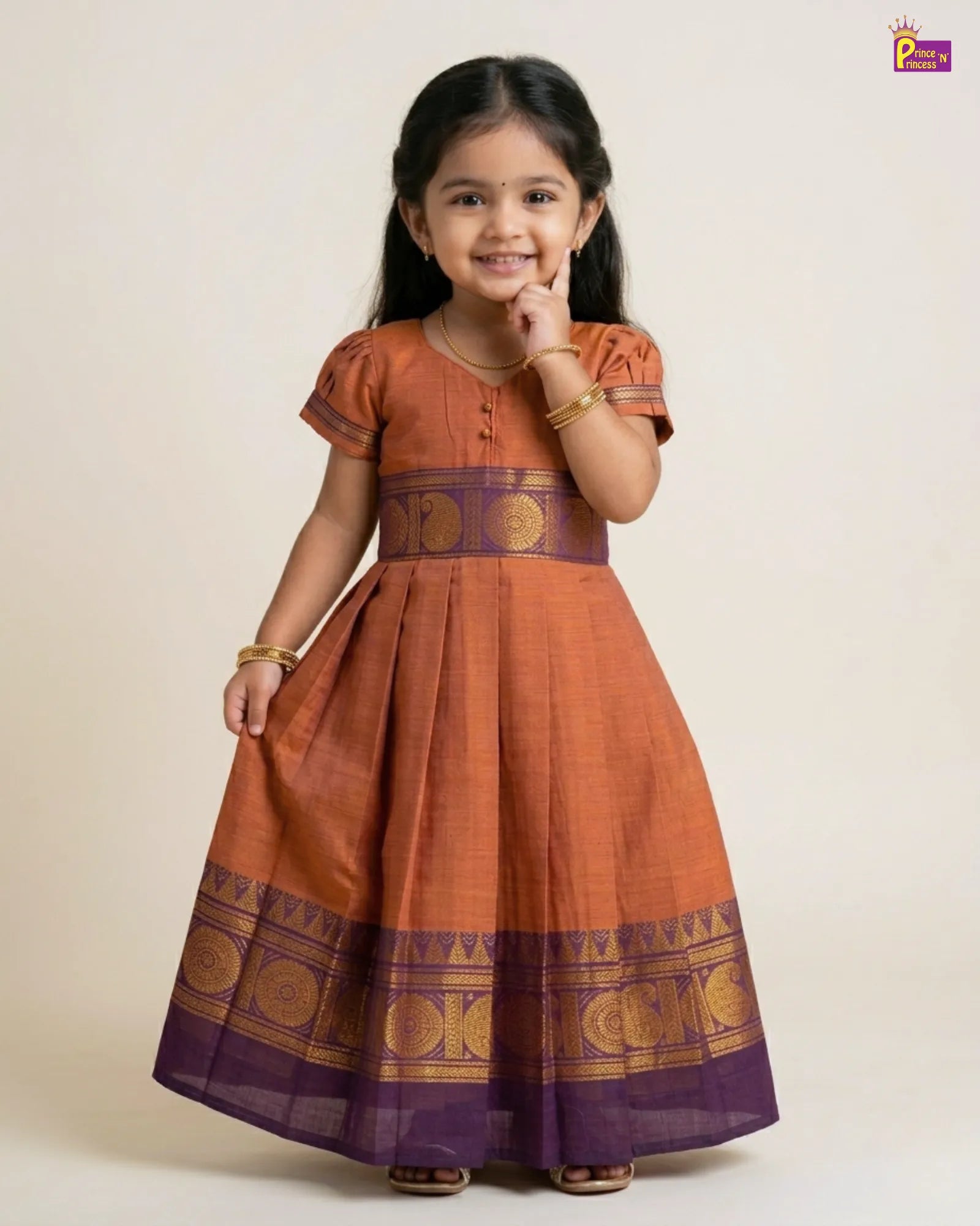 Young girl wearing an orange and purple traditional dress with gold patterns on a beige background