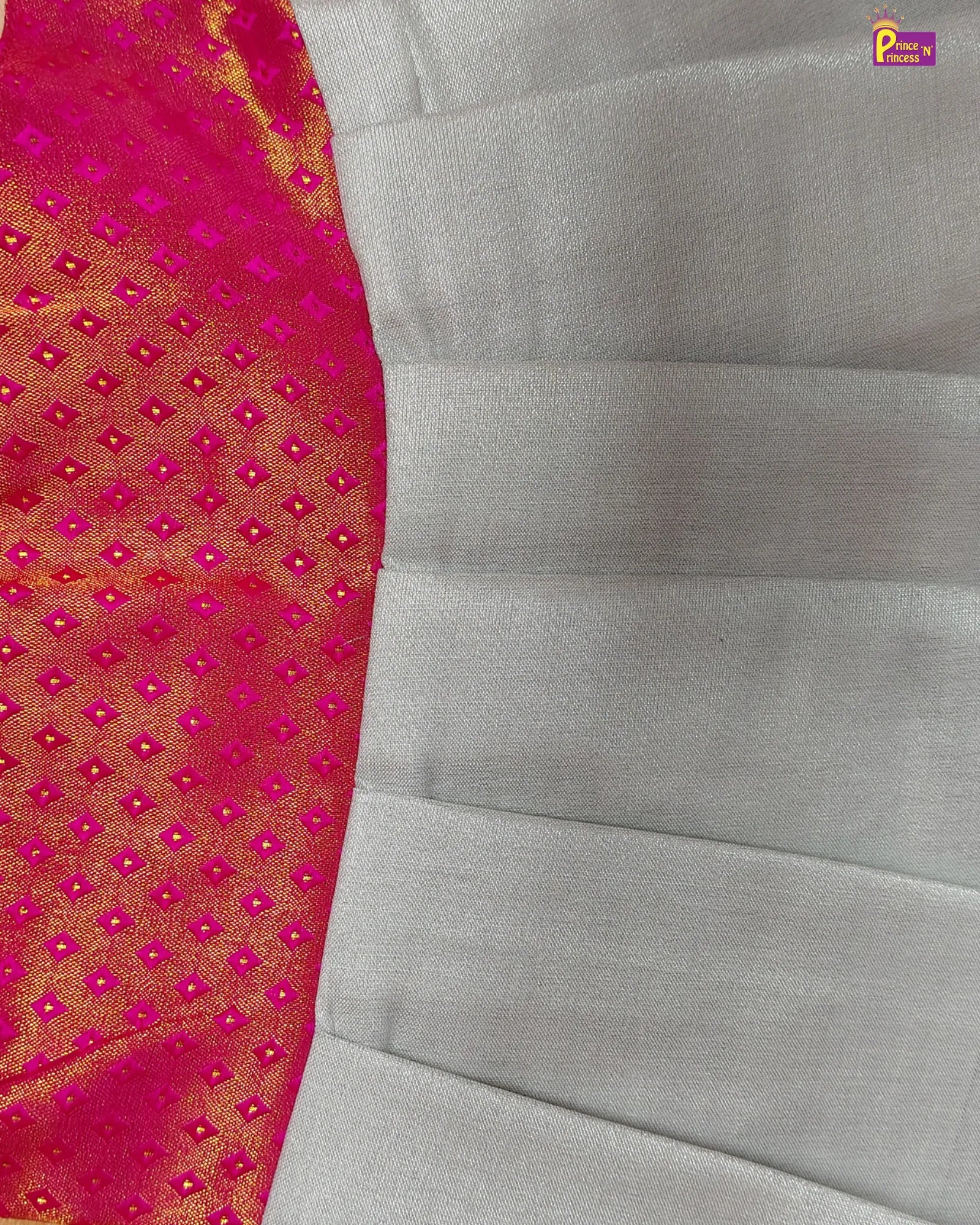 Close-up of a saree with pink and gold border and gray fabric.