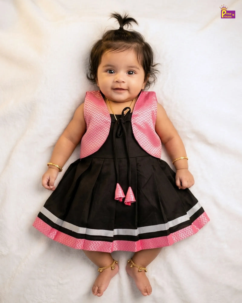 Baby wearing a black dress with pink accents on a white background