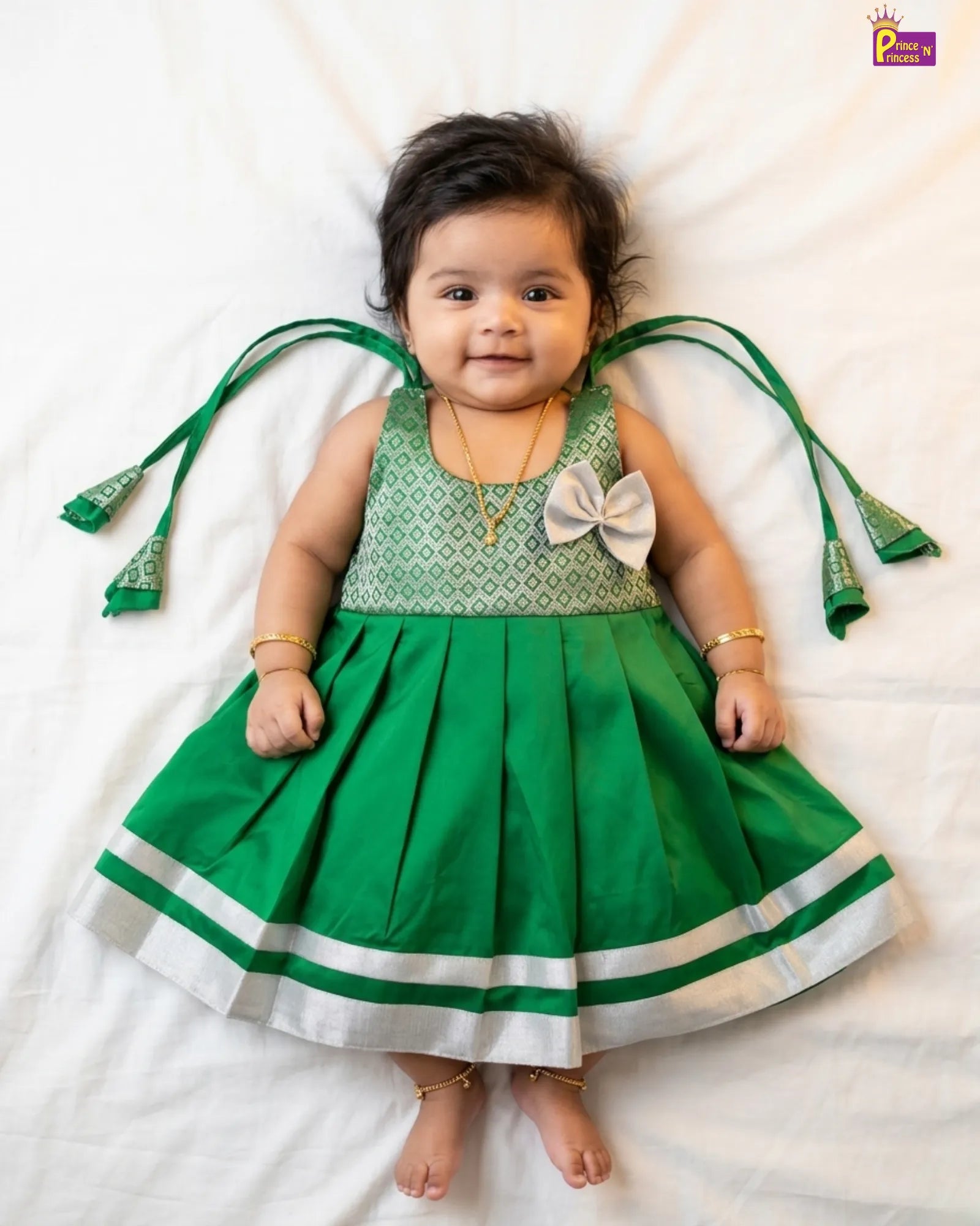 Baby wearing a green dress with decorative elements on a white background