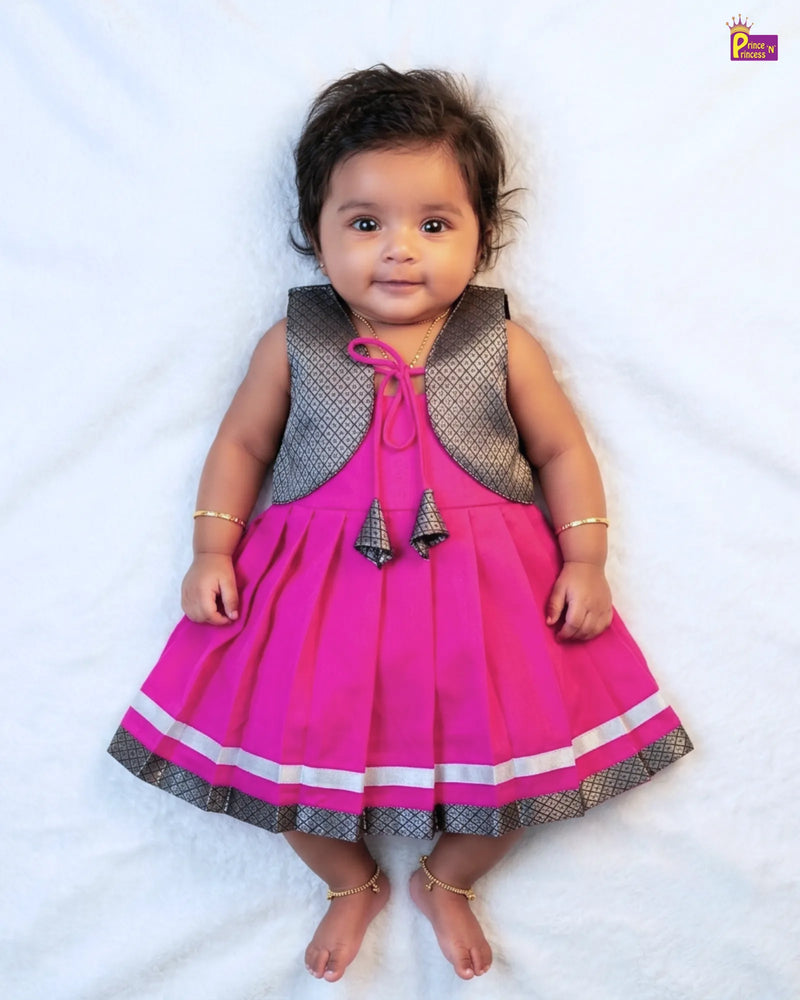 Baby wearing a pink dress with a gray vest on a white background