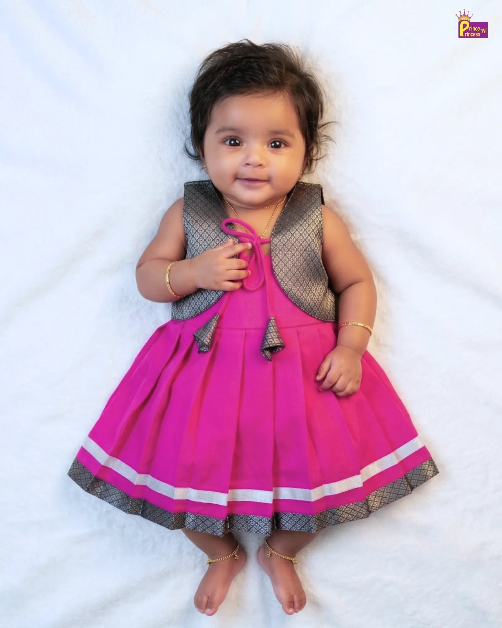 Baby wearing a pink dress with a gray vest on a white background