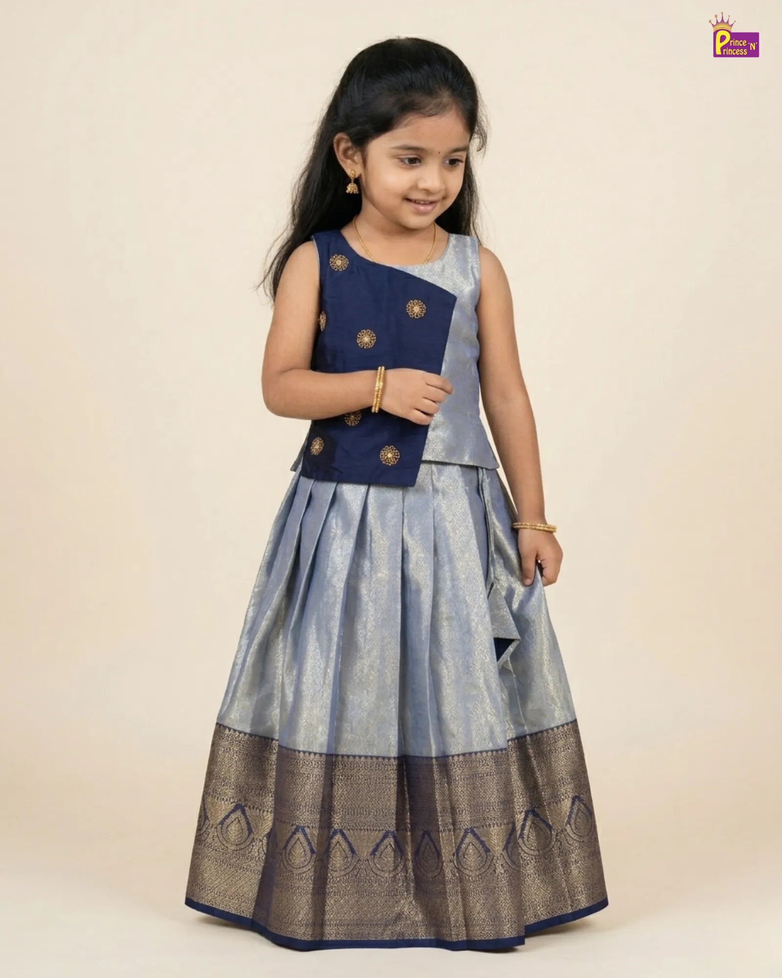 Young girl wearing a traditional outfit with a navy blue top and gray skirt on a beige background