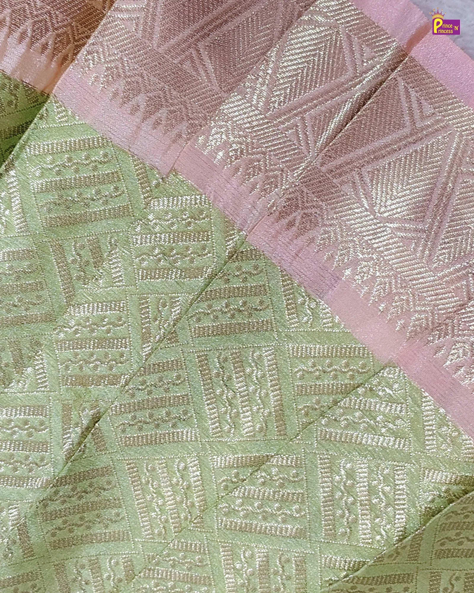 Close-up of a fabric with intricate patterns in green, pink, and white.