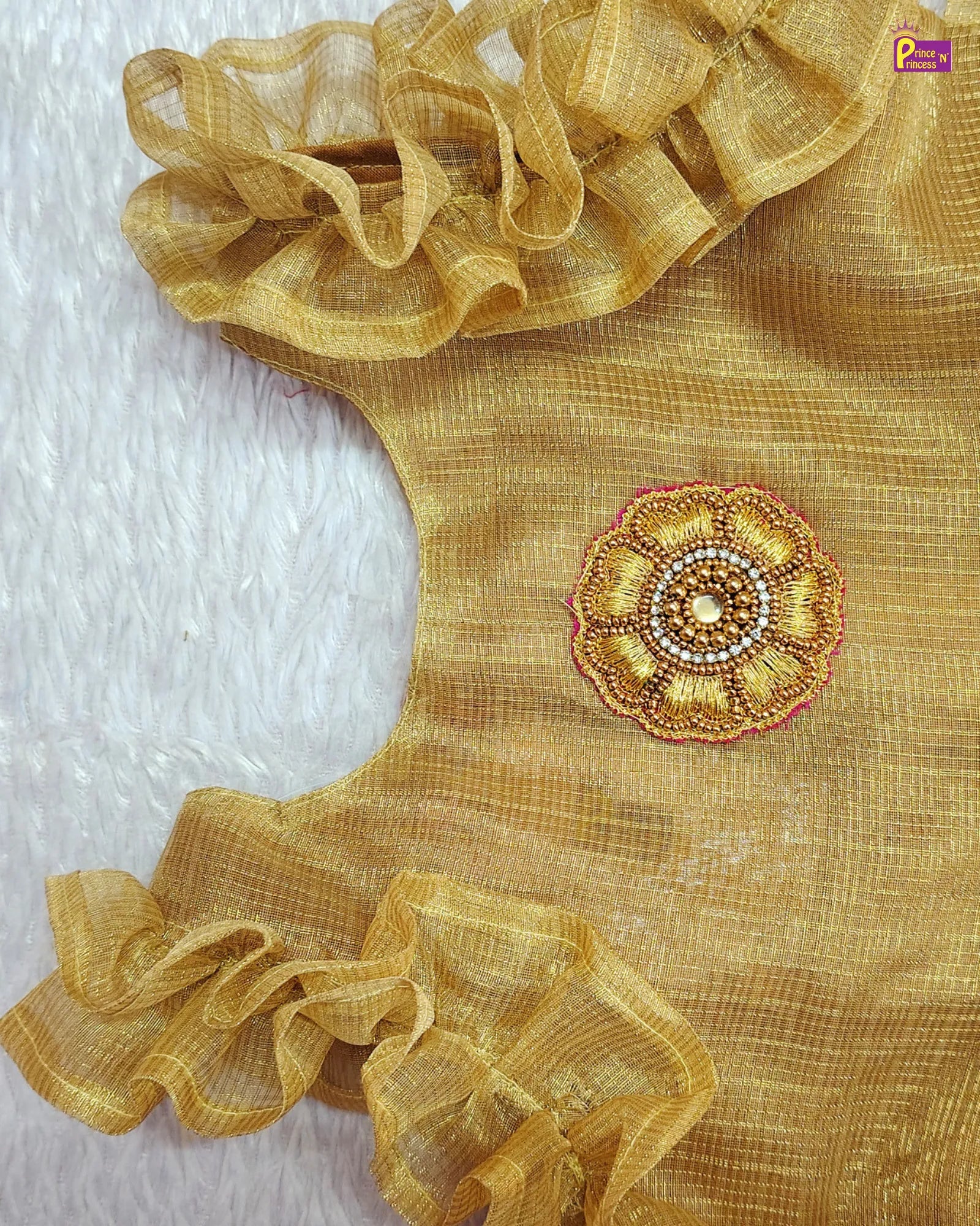 Gold blouse with ruffled sleeves and floral embellishment on a white background