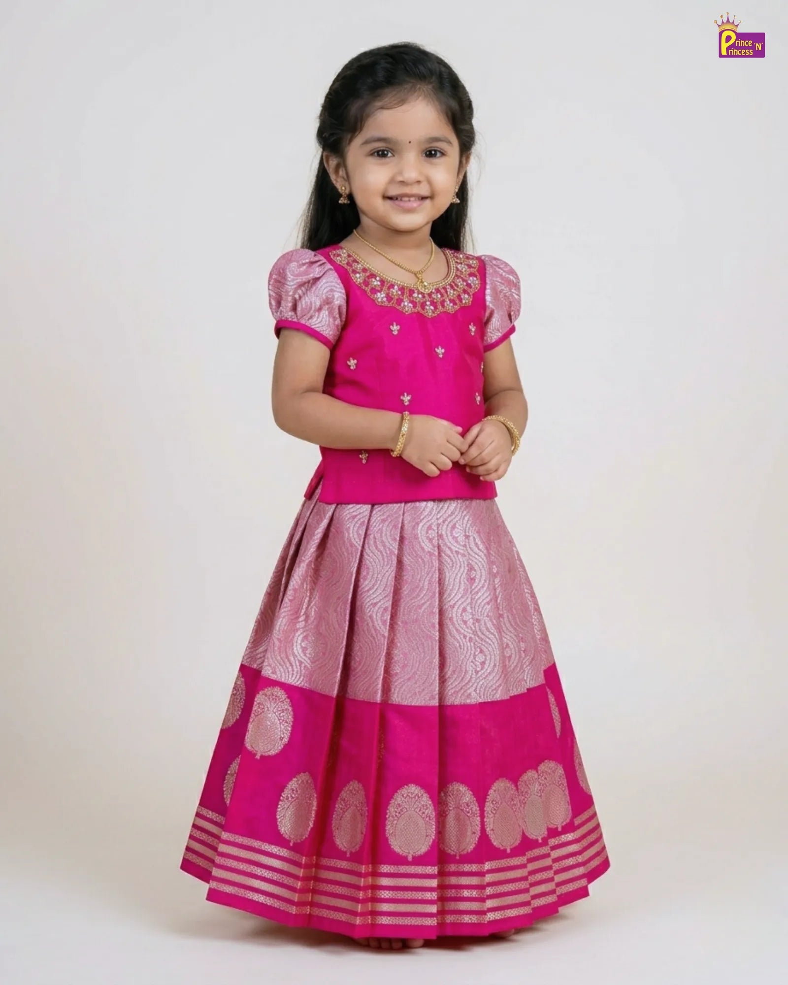 Young girl wearing a pink traditional outfit with a white background pattu pavadai prince n princess