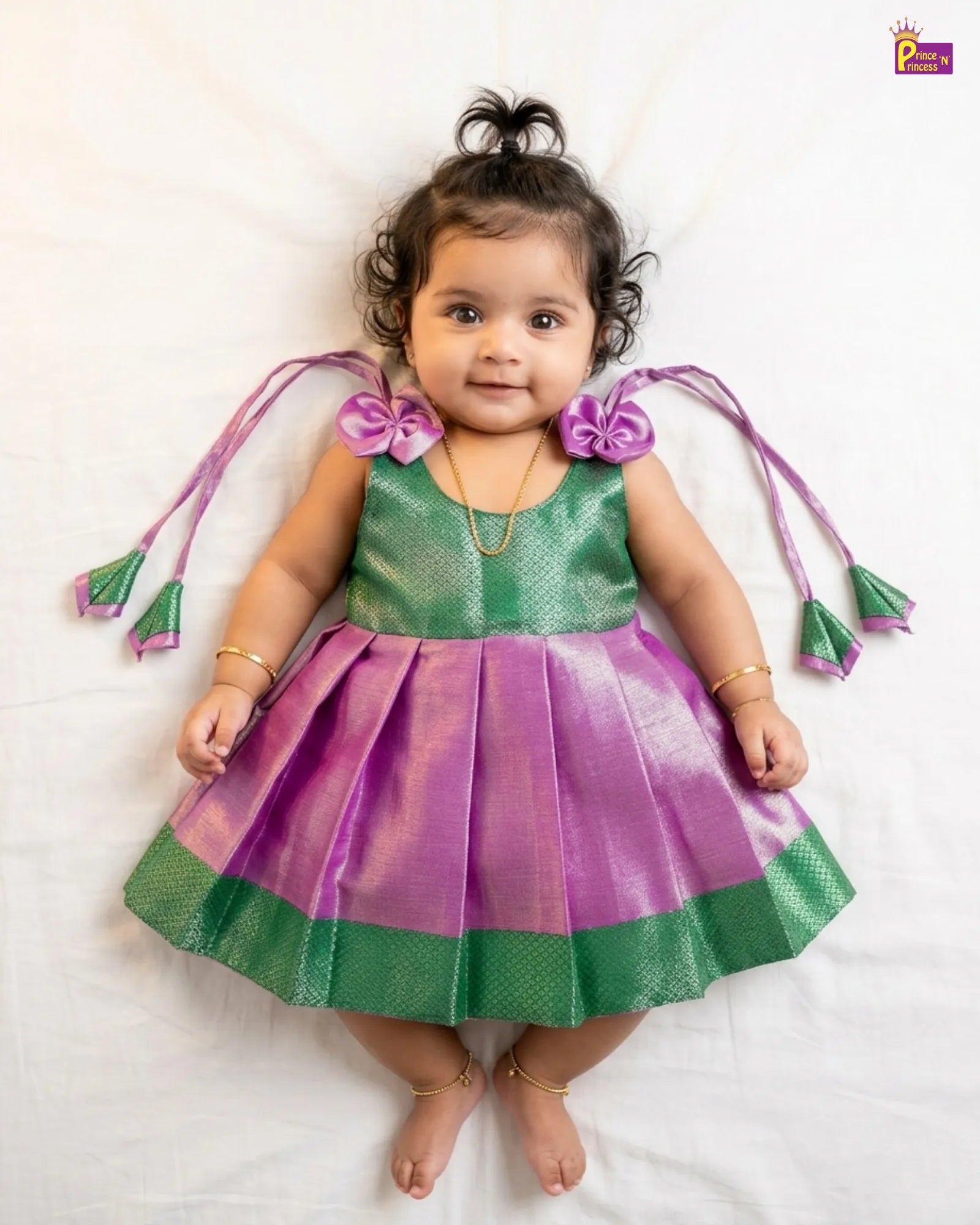 Child wearing a green and purple dress with decorative elements on a white background