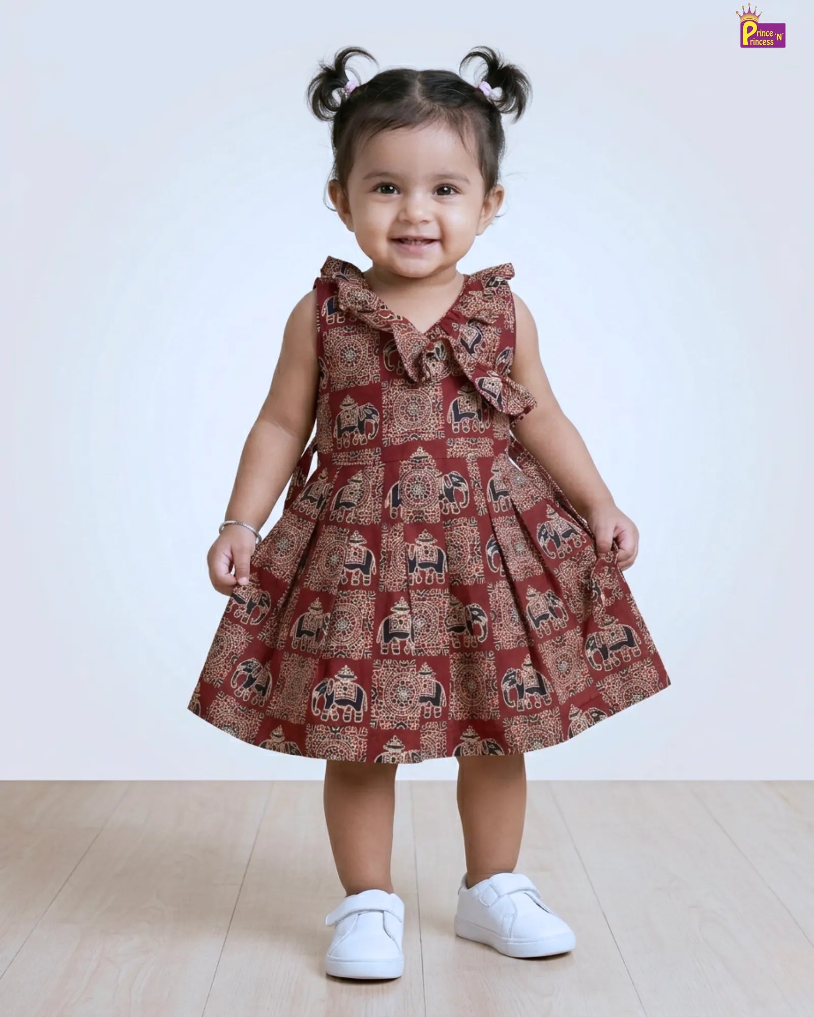 Child wearing a patterned dress with white shoes on a beige background